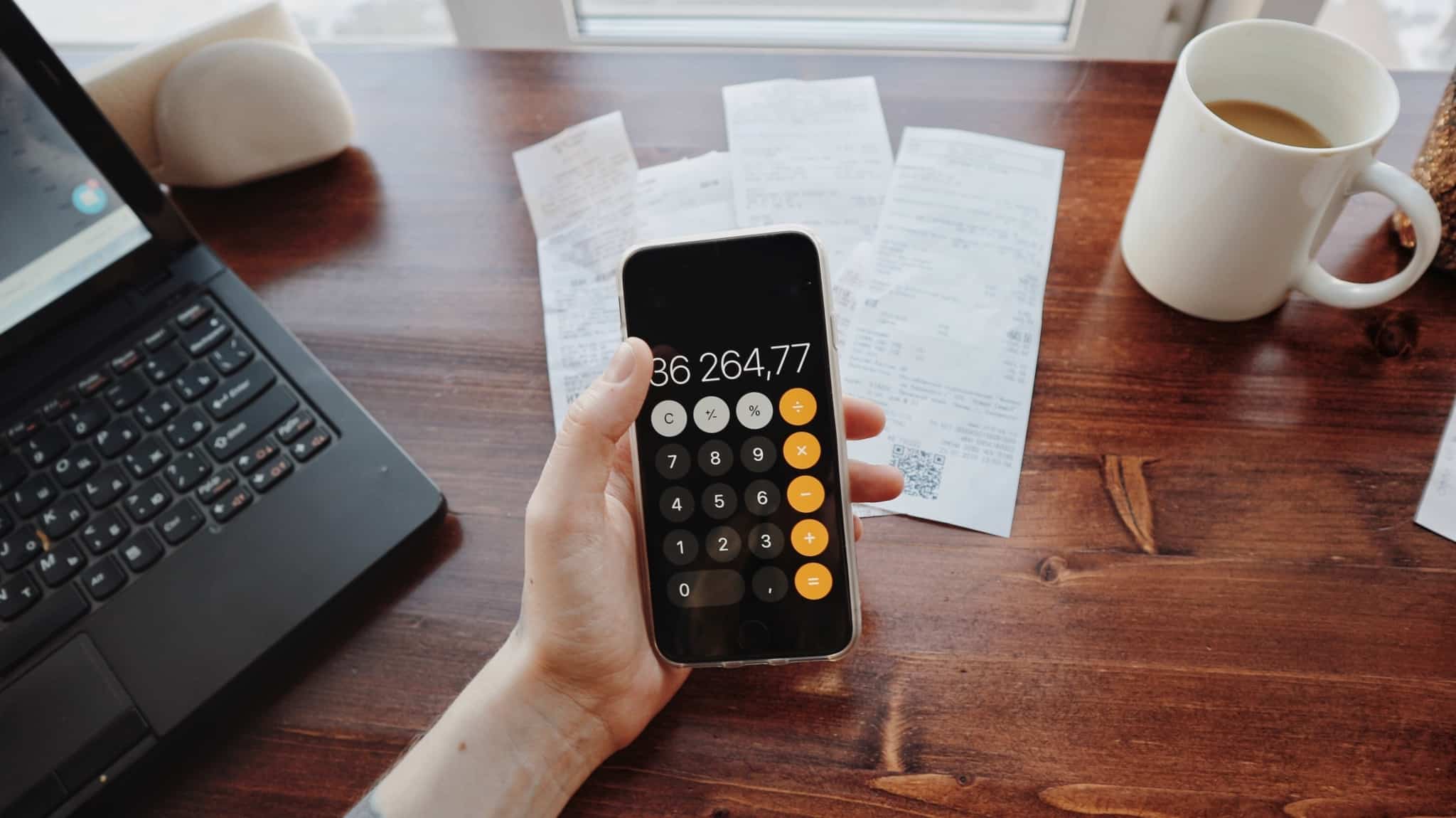 homem segura telemóvel com calculadora