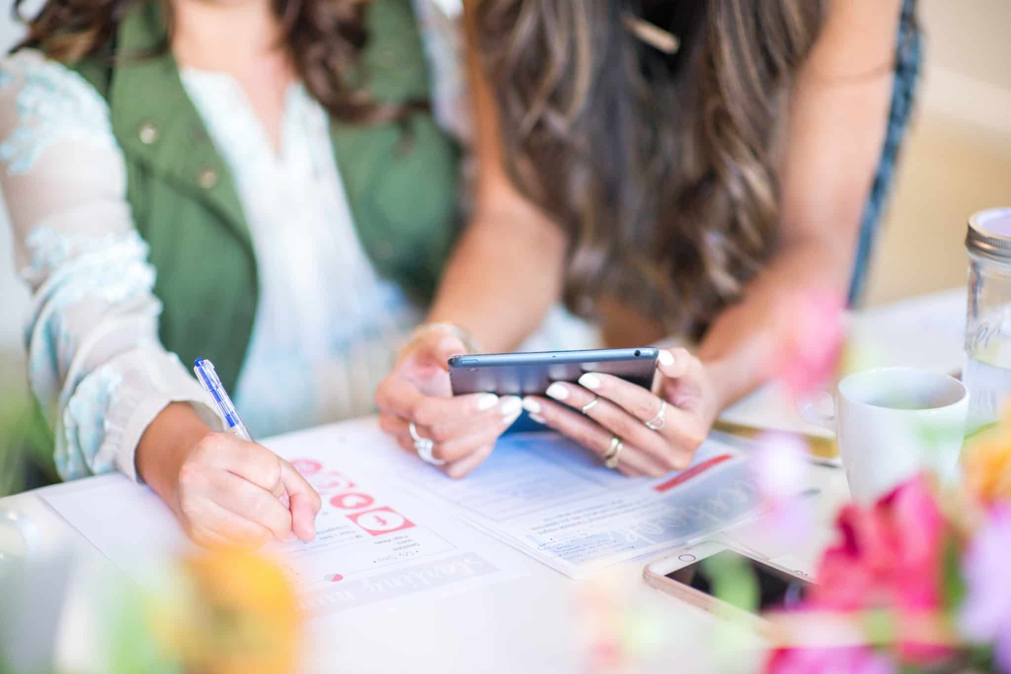 duas mulheres a tomar notas e a ver no smartphone