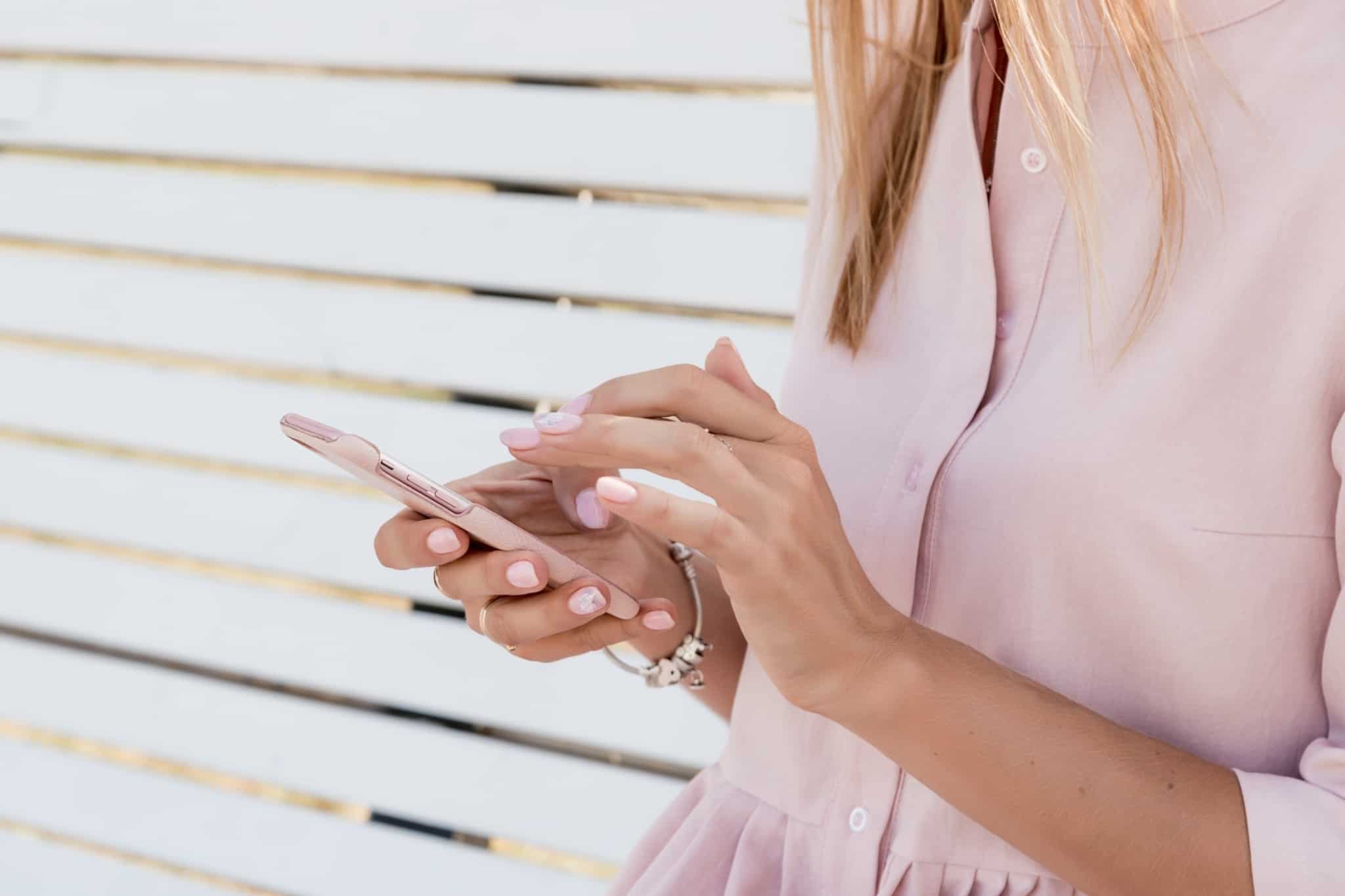 mulher vestida de rosa mexe em telemóvel
