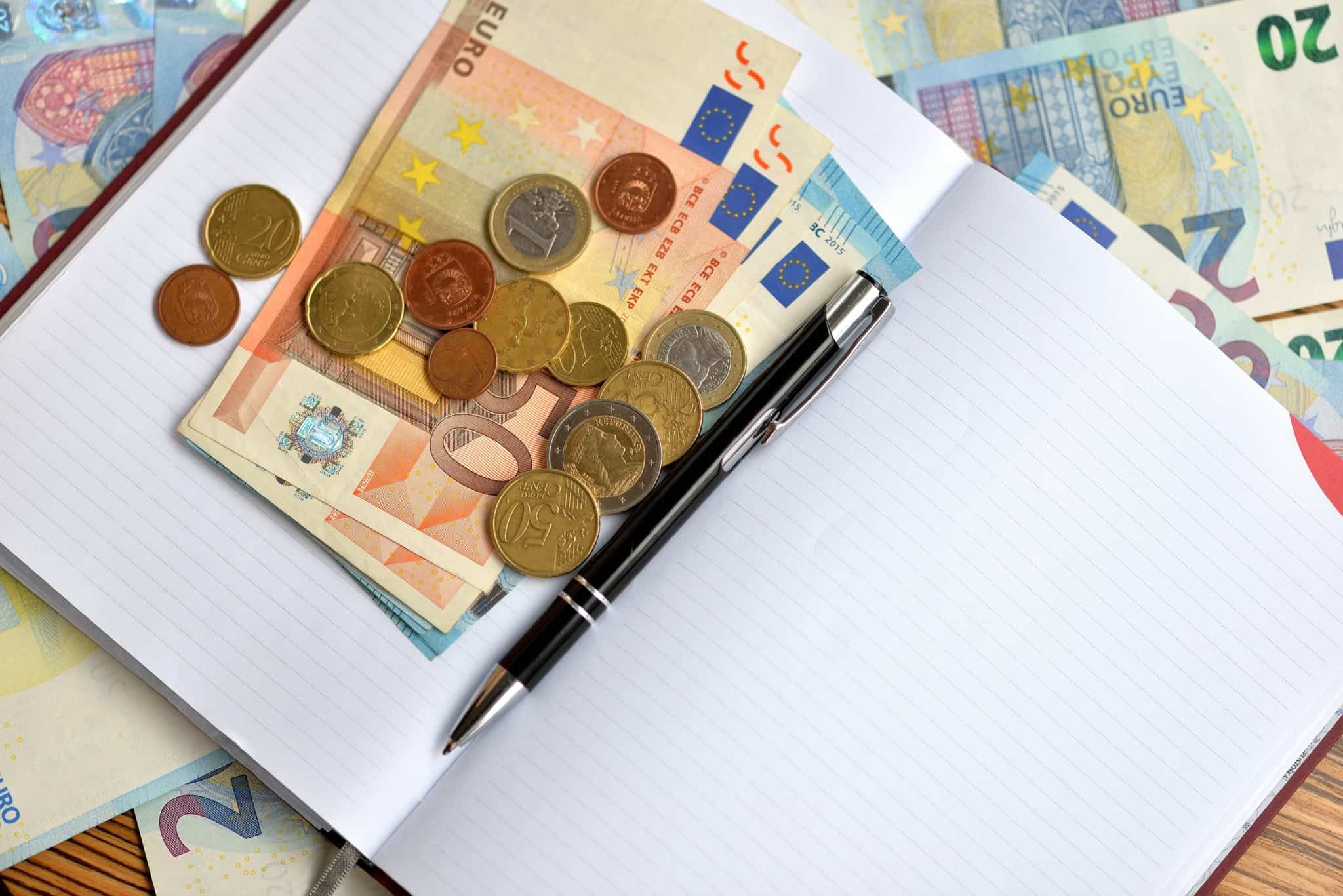 caderno aberto com notas e moedas de euro