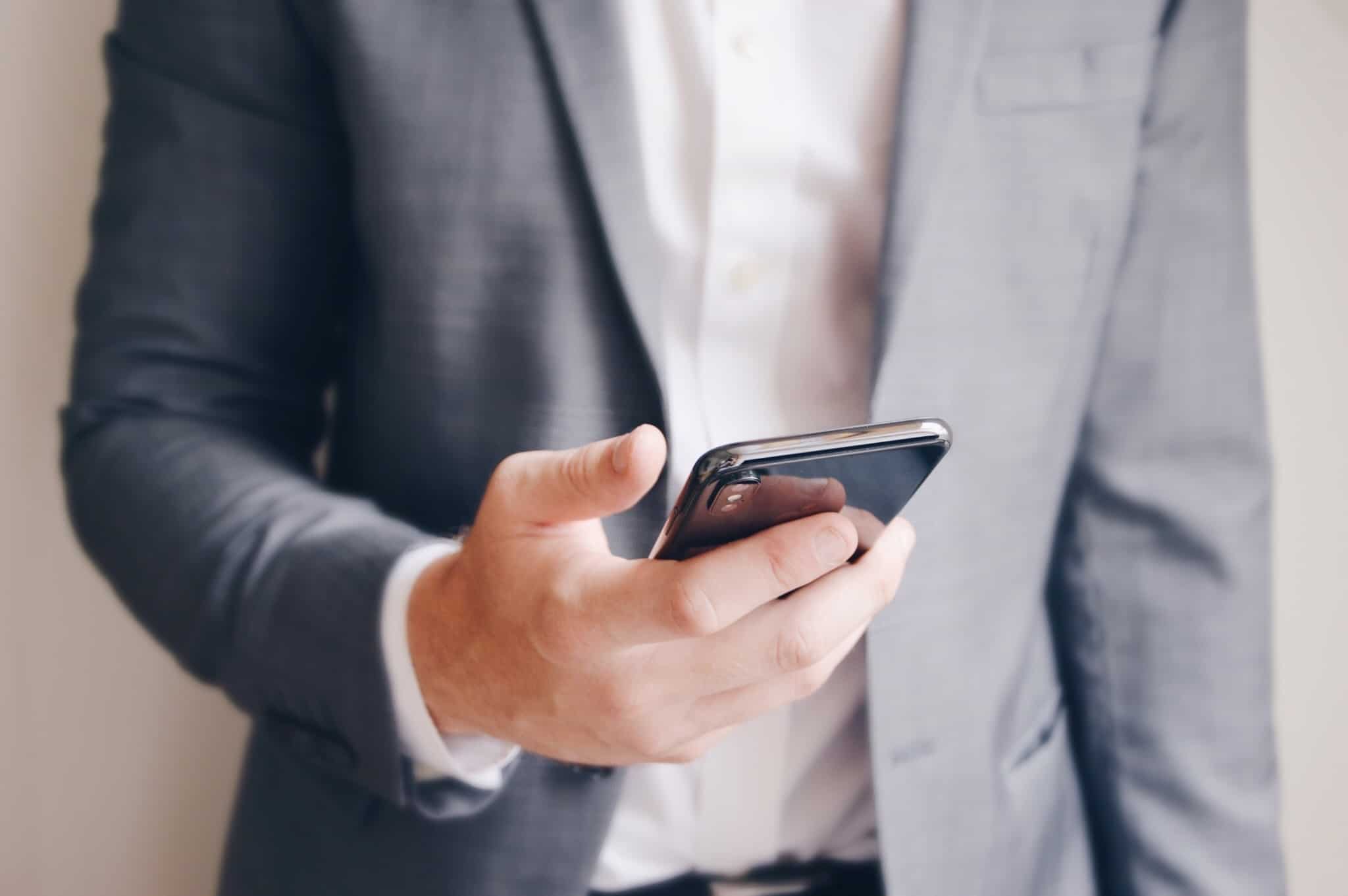 homem com fato e gravata a segurar no smartphone