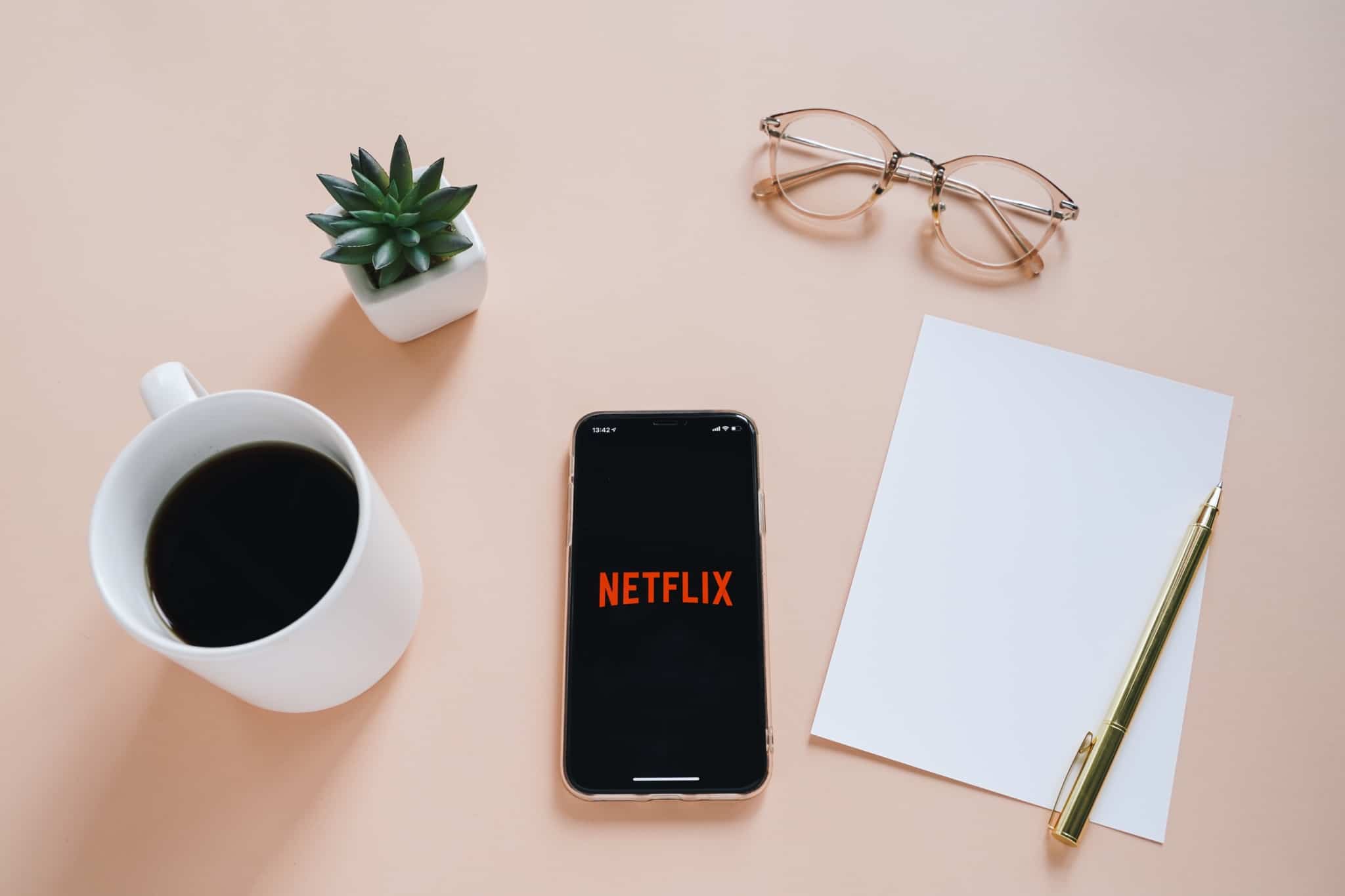 caderno chavena de cafe e telemovel com netflix