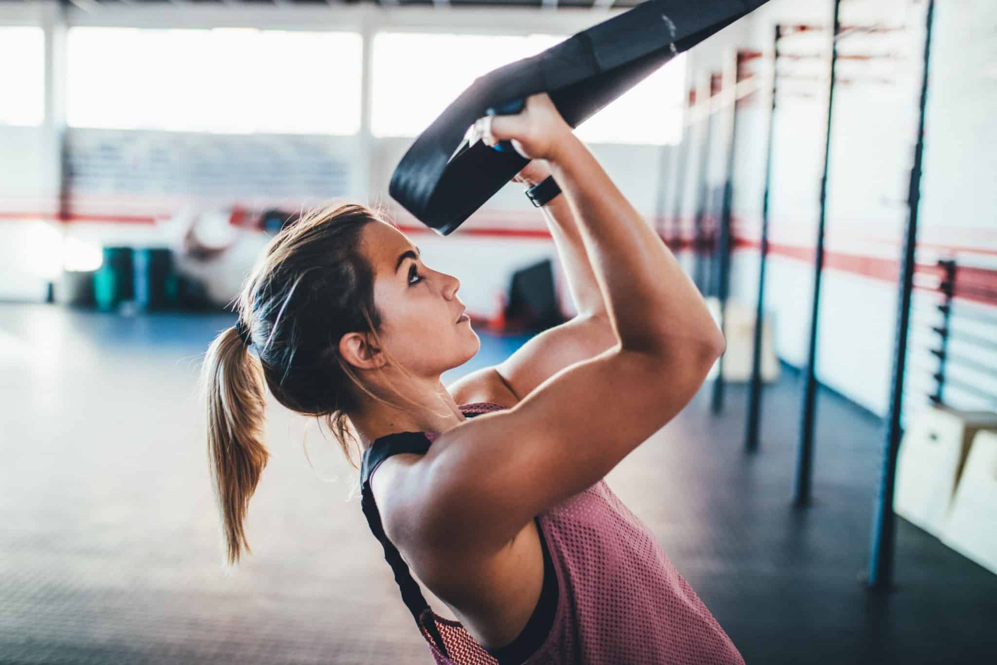 mulher a fazer exercicio fisico com trx no ginasio