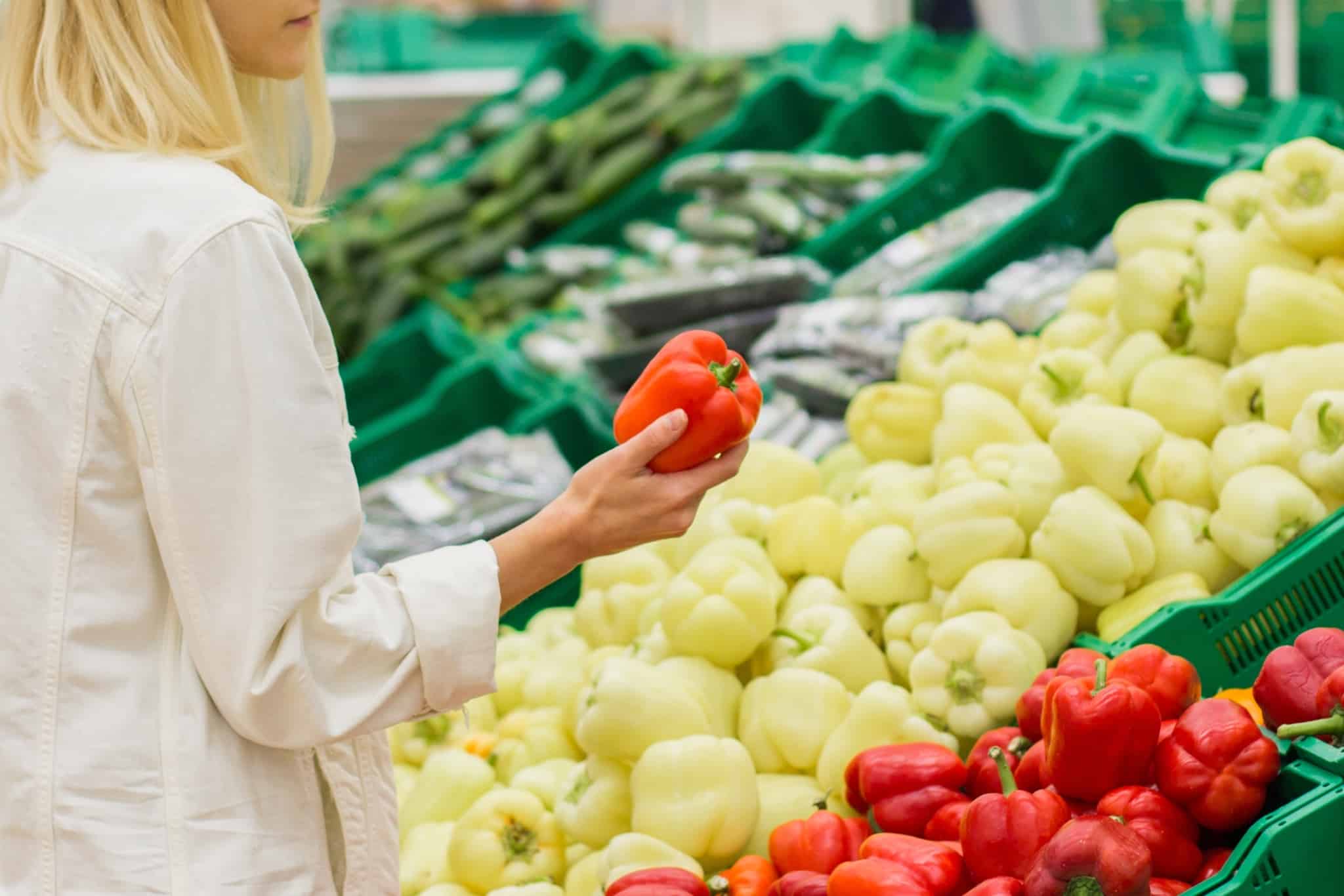 jovem mulher às compras no supermercado, a escolher os vegetais mais frecos, parte da sua dieta vegetariana