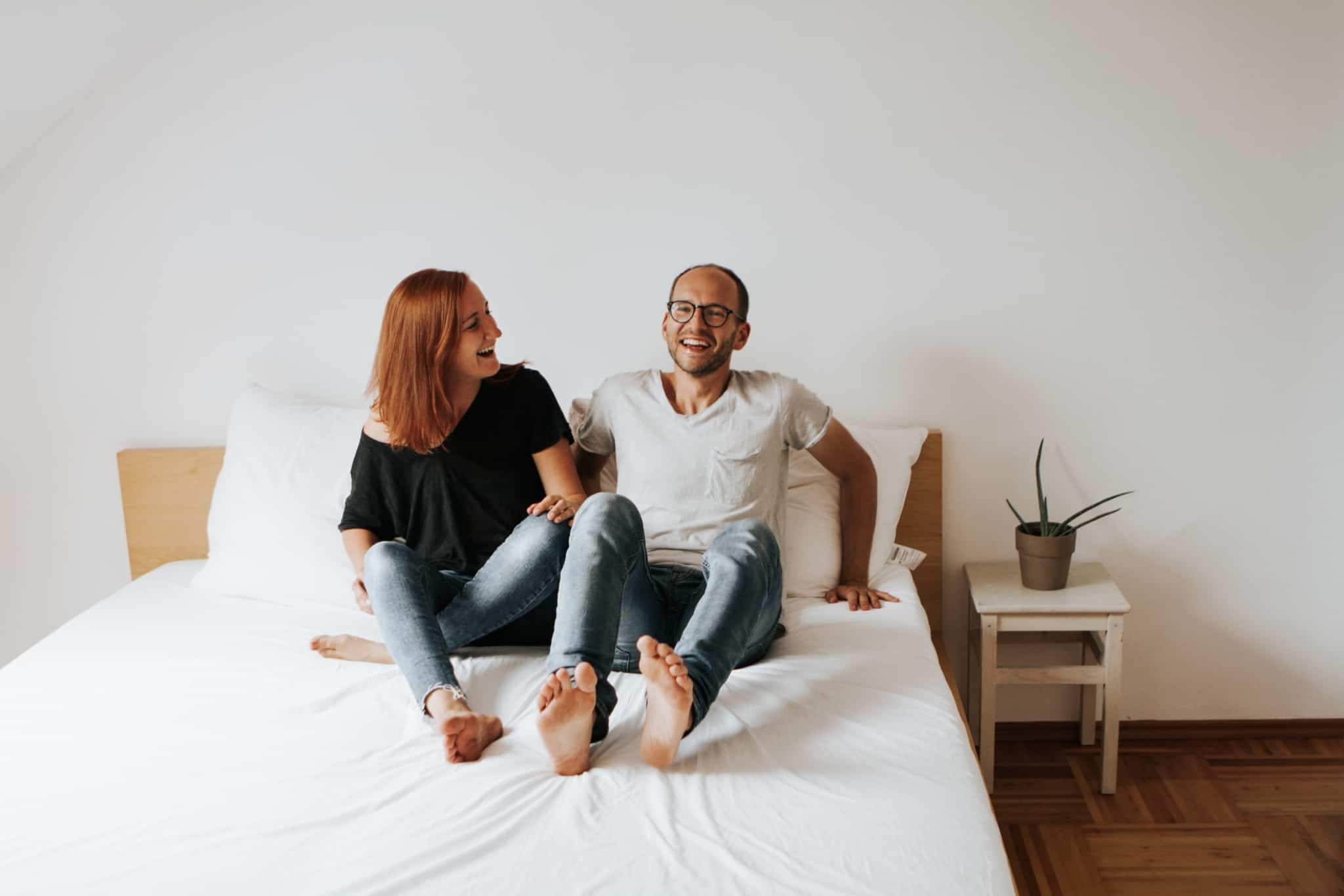 casal sorridente deitado na cama