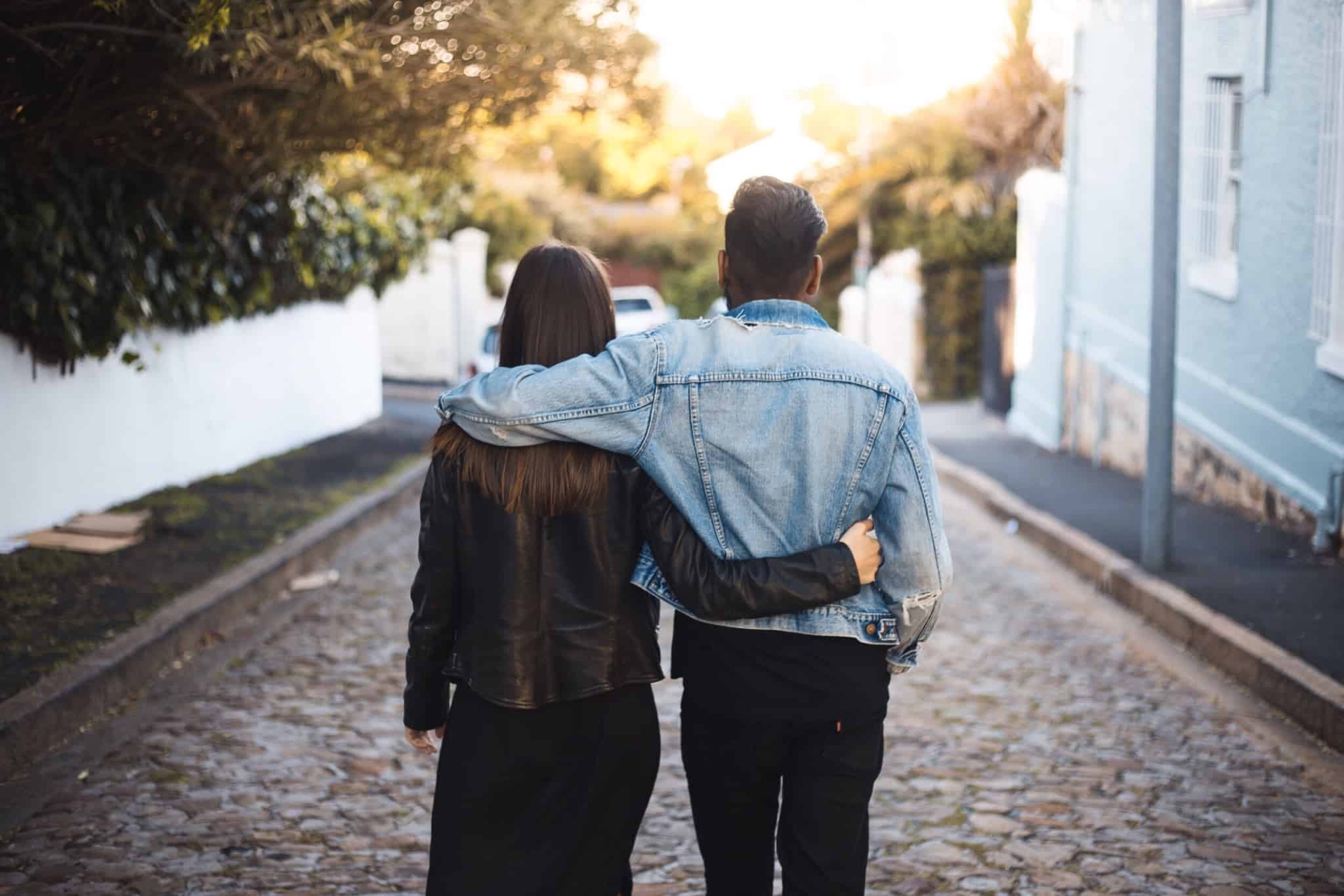 casal de costas a andar na rua com os braços à volta um do outro