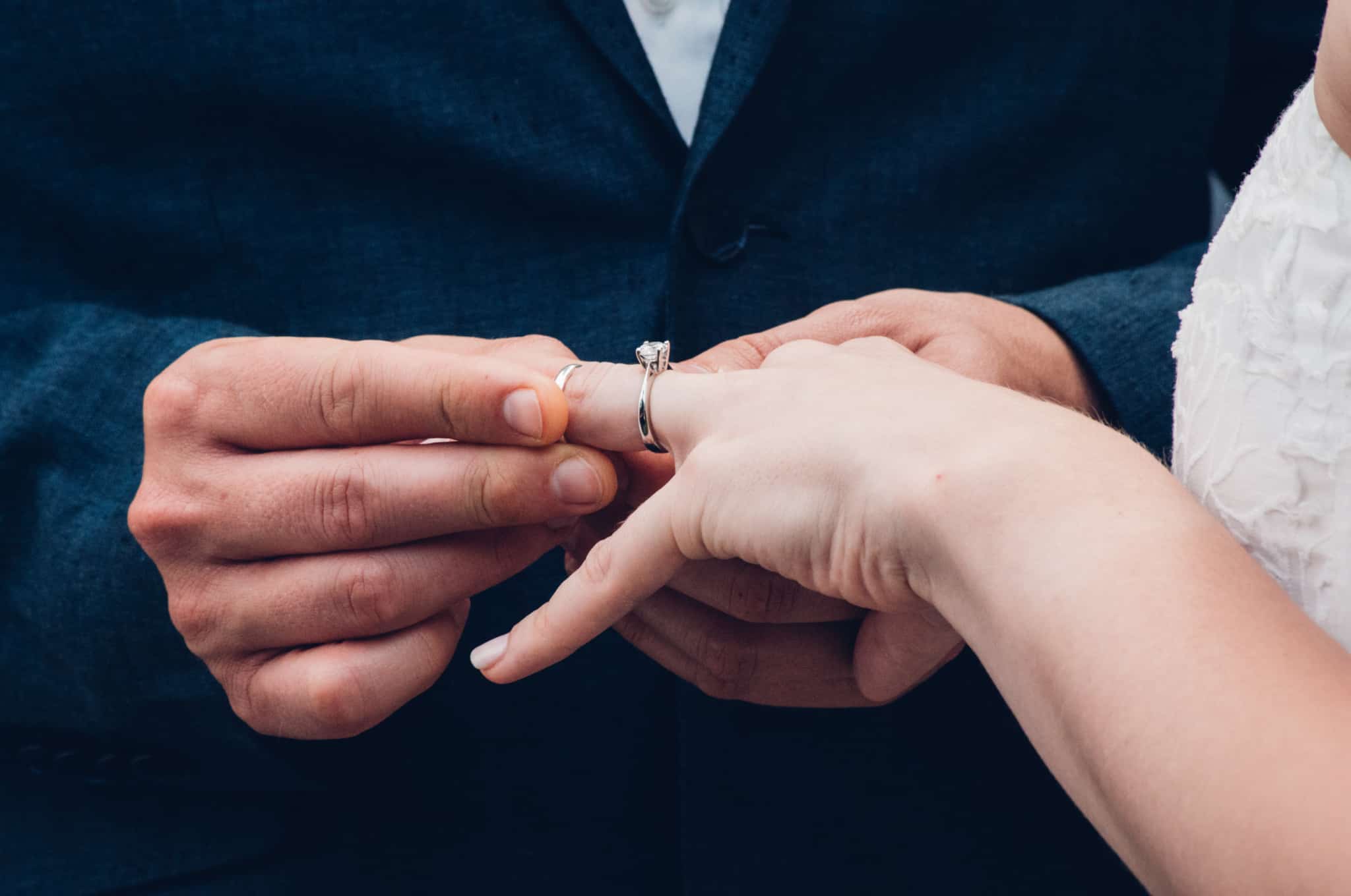 casal a casar-se em que o noivo coloca a aliança no dedo da noiva