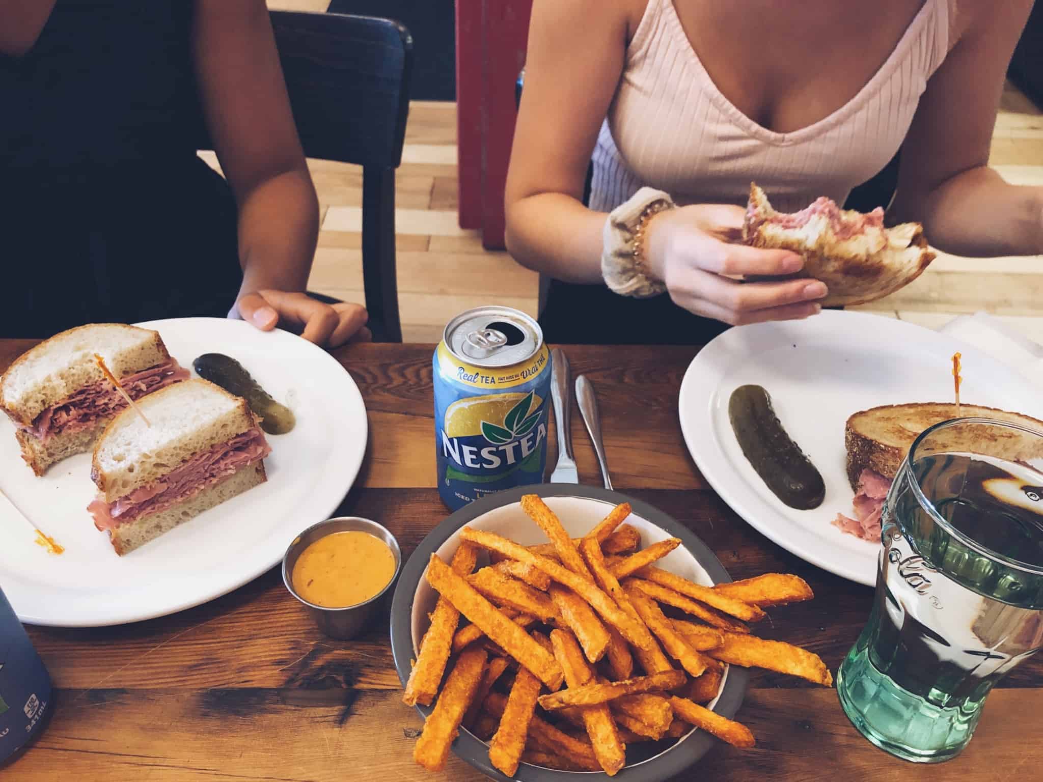 duas pessoas a almoçar sandes e batatas fritas