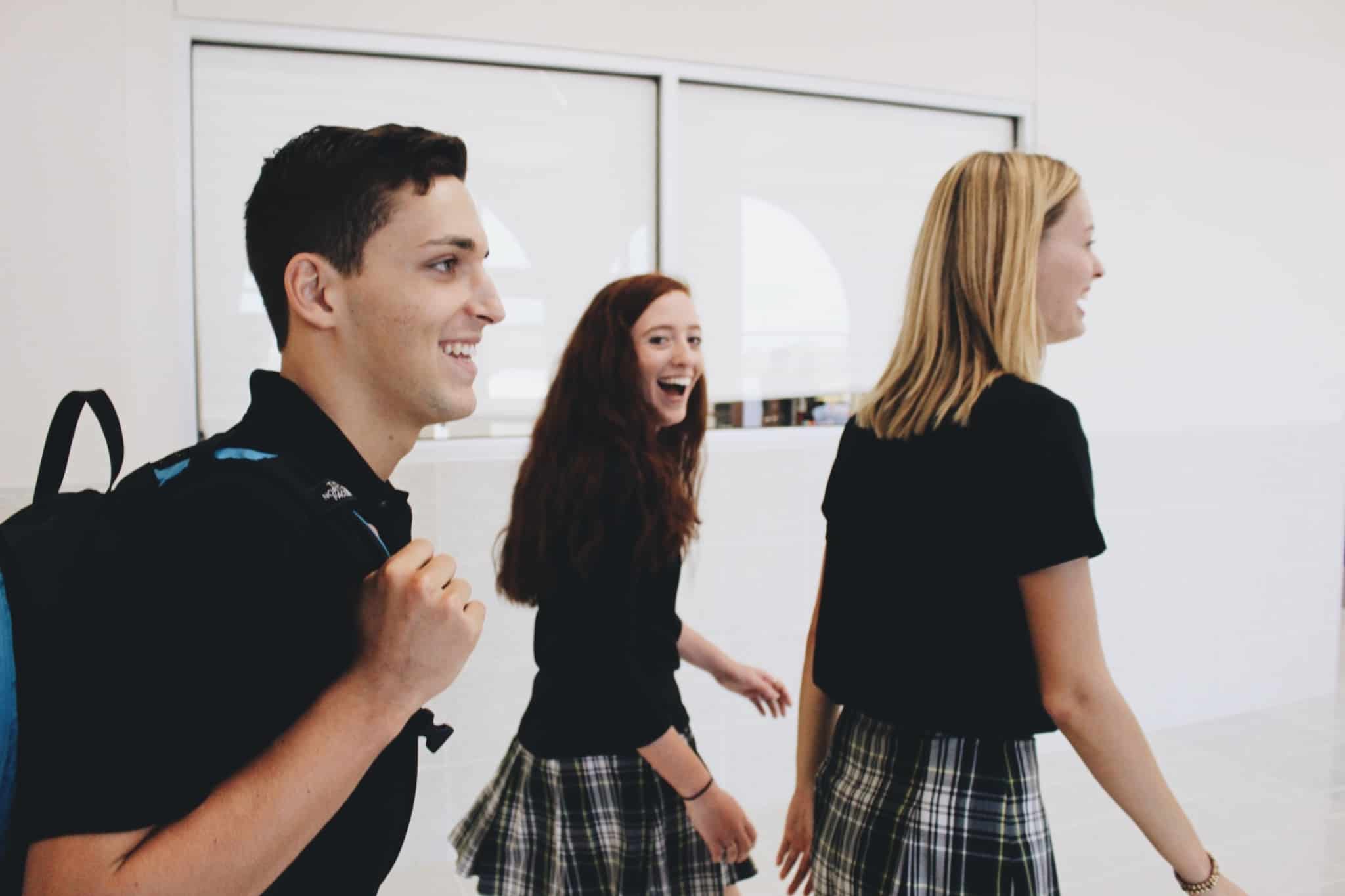 tres alunos sorridentes a passear no corredor