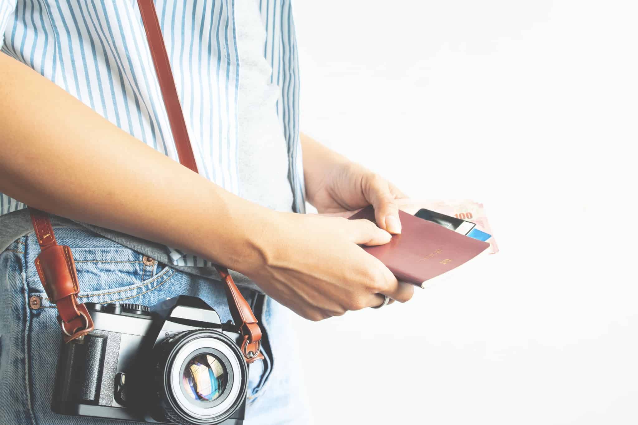 pessoa com maquina fotografica pendurada ao ombro a mexer na carteira com cartões