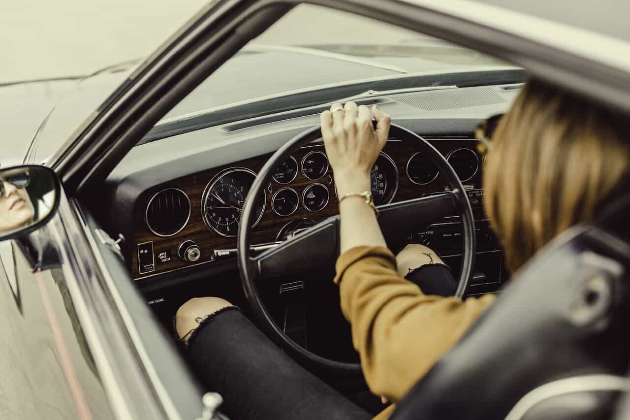 mulher a guiar um carro antigo