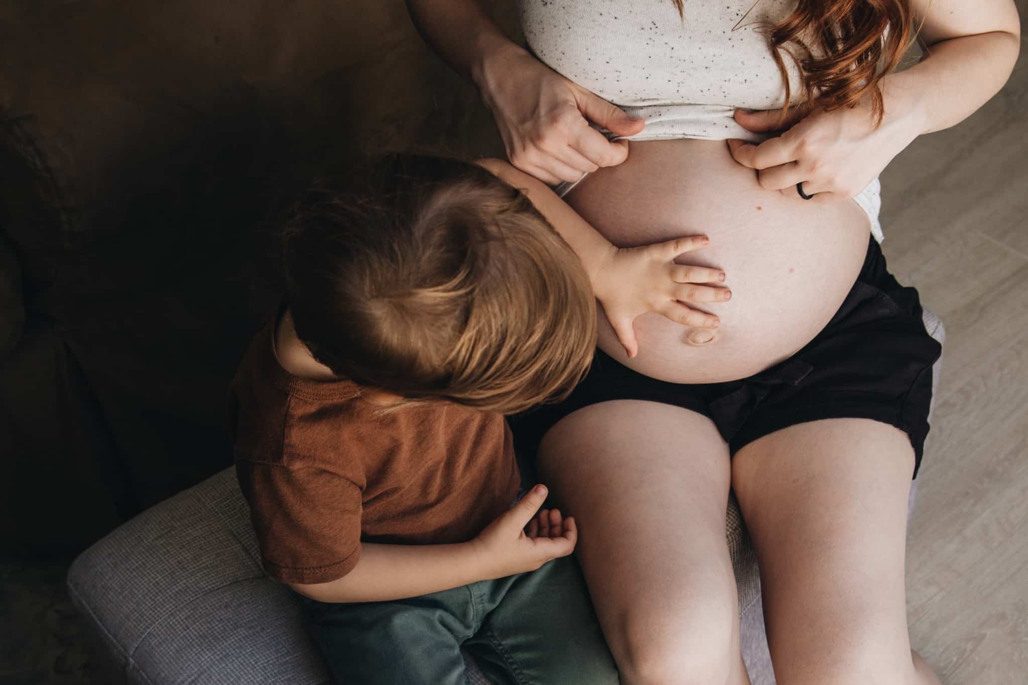 criança a tocar na barriga da grávida