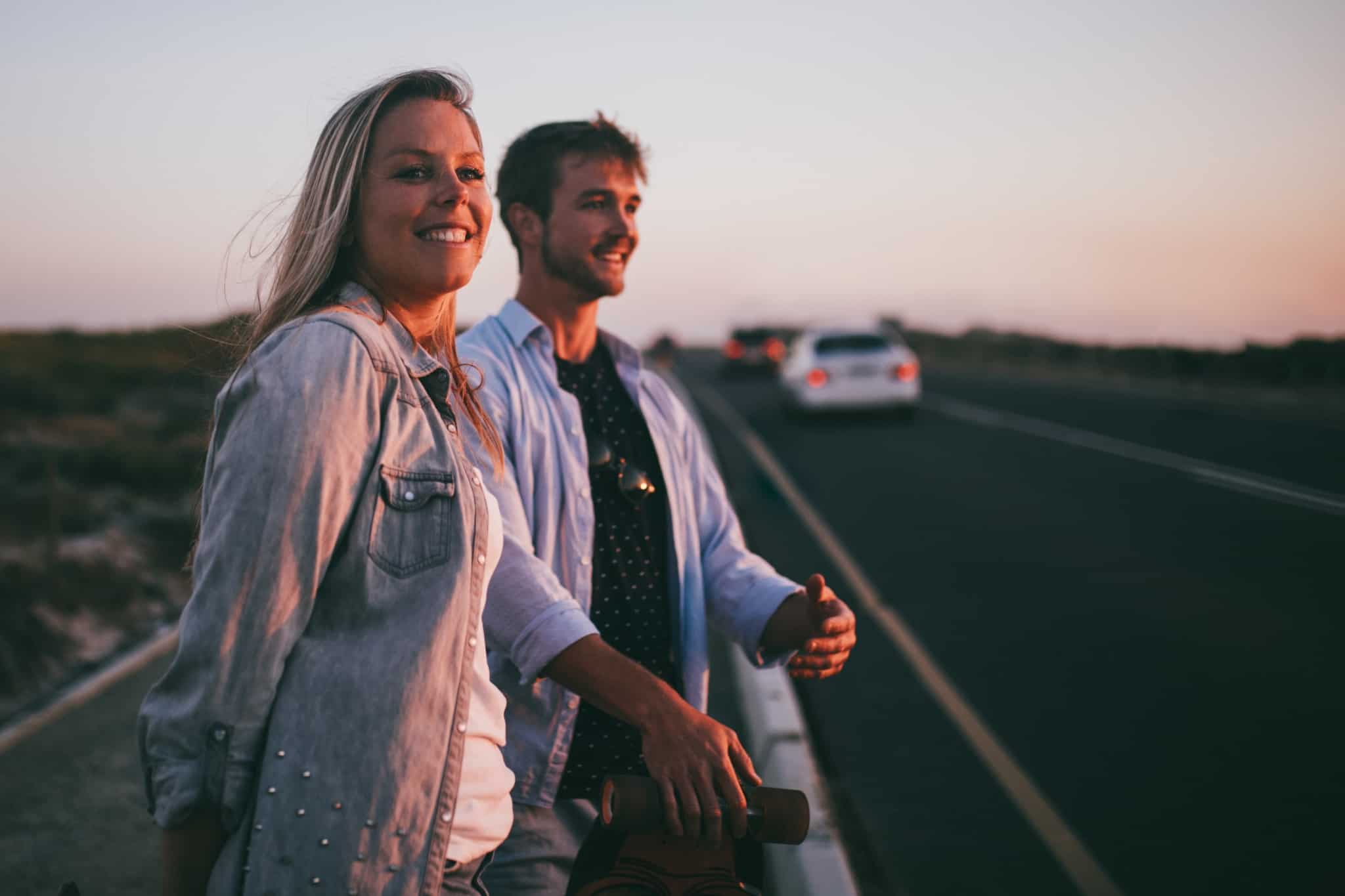 casal à beira da estrada a ver os carros a passar ao por do sol