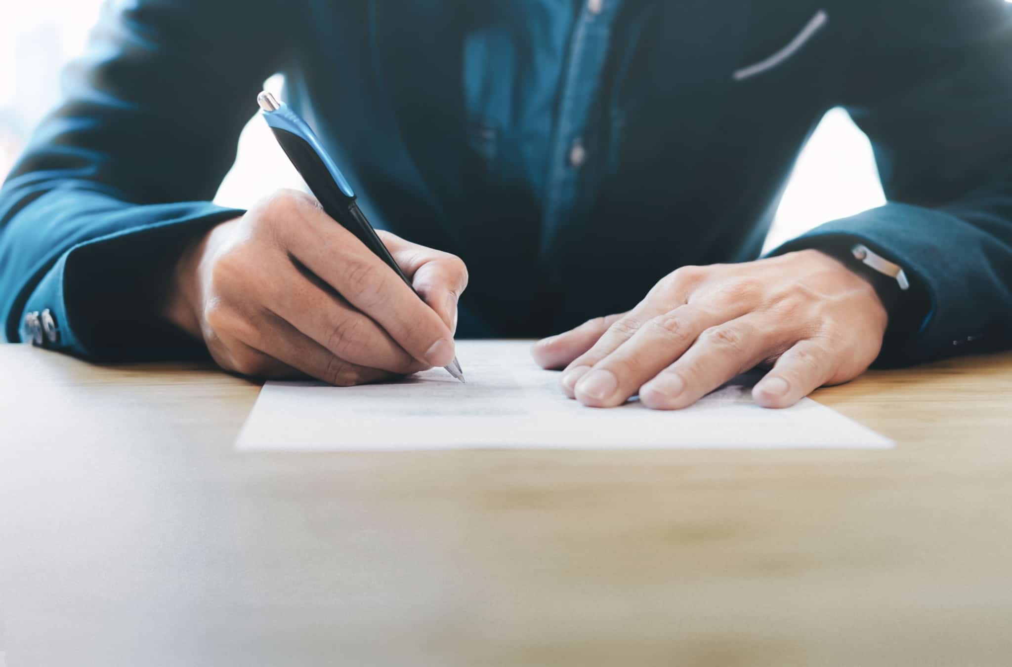 pessoa a assinar documentos após a suspensão do contrato de trabalho