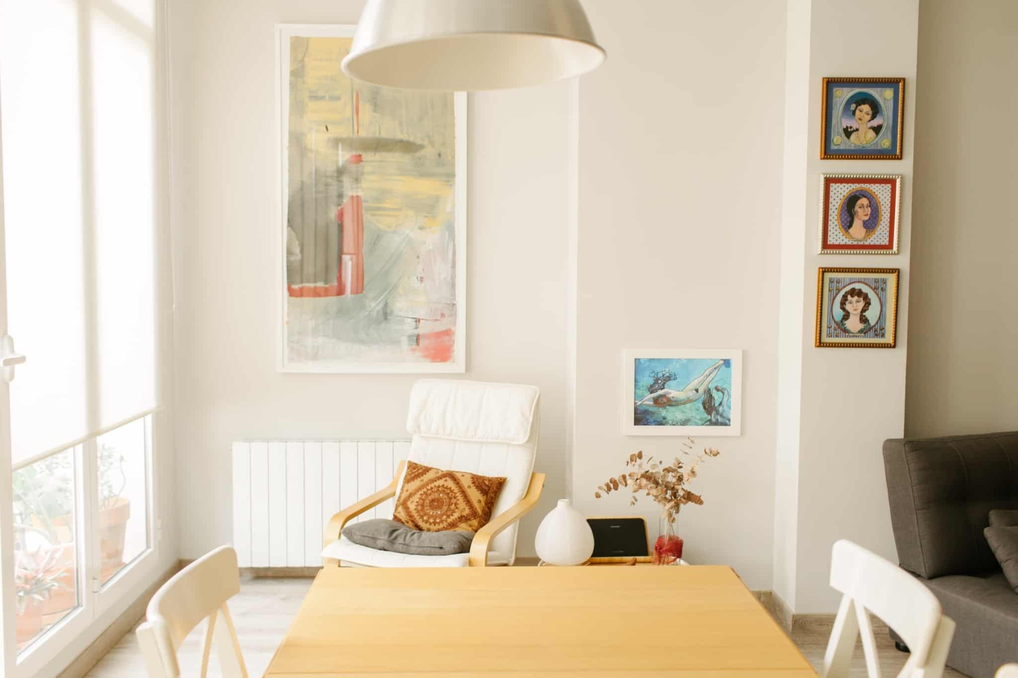 sala de estar com mesa de madeira e um cadeirão branco com almofada laranja