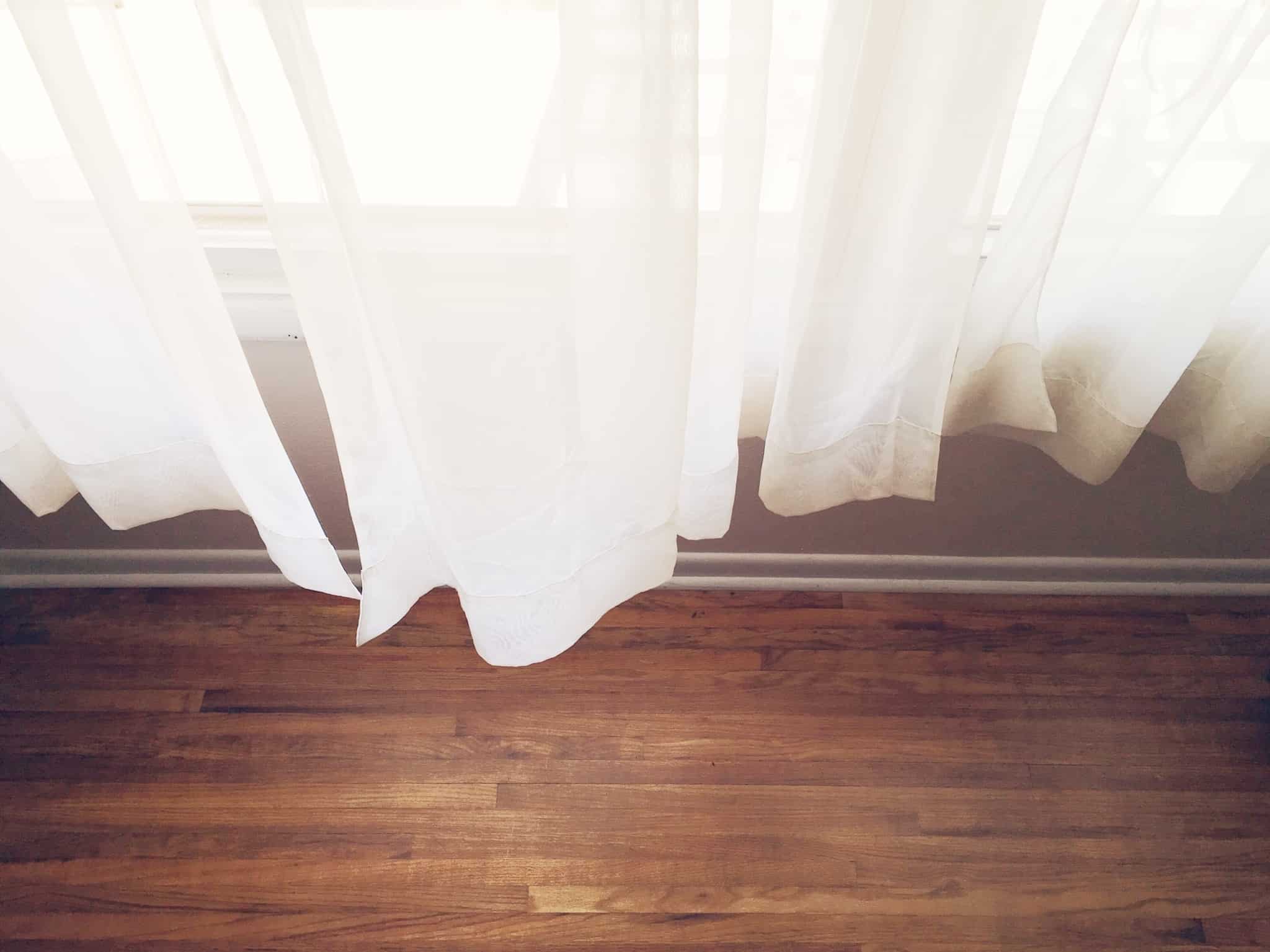 cortinas bancas de uma janela e um chao de madeira
