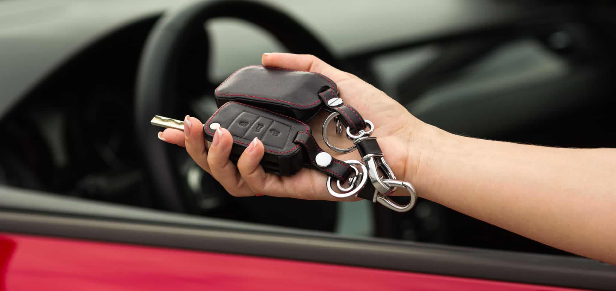 Mulher a pegar em chaves de um carro vermelho