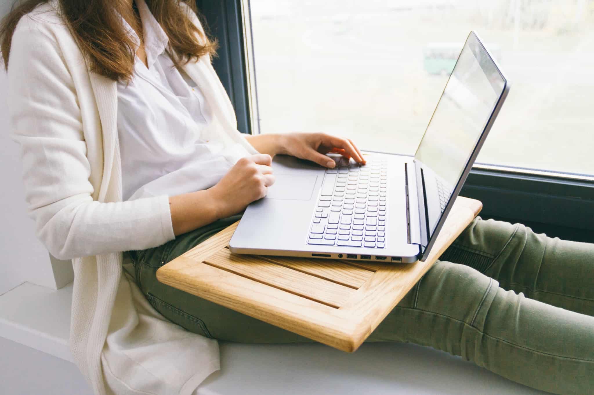 rapariga com laptop no colo a olhar para a janela