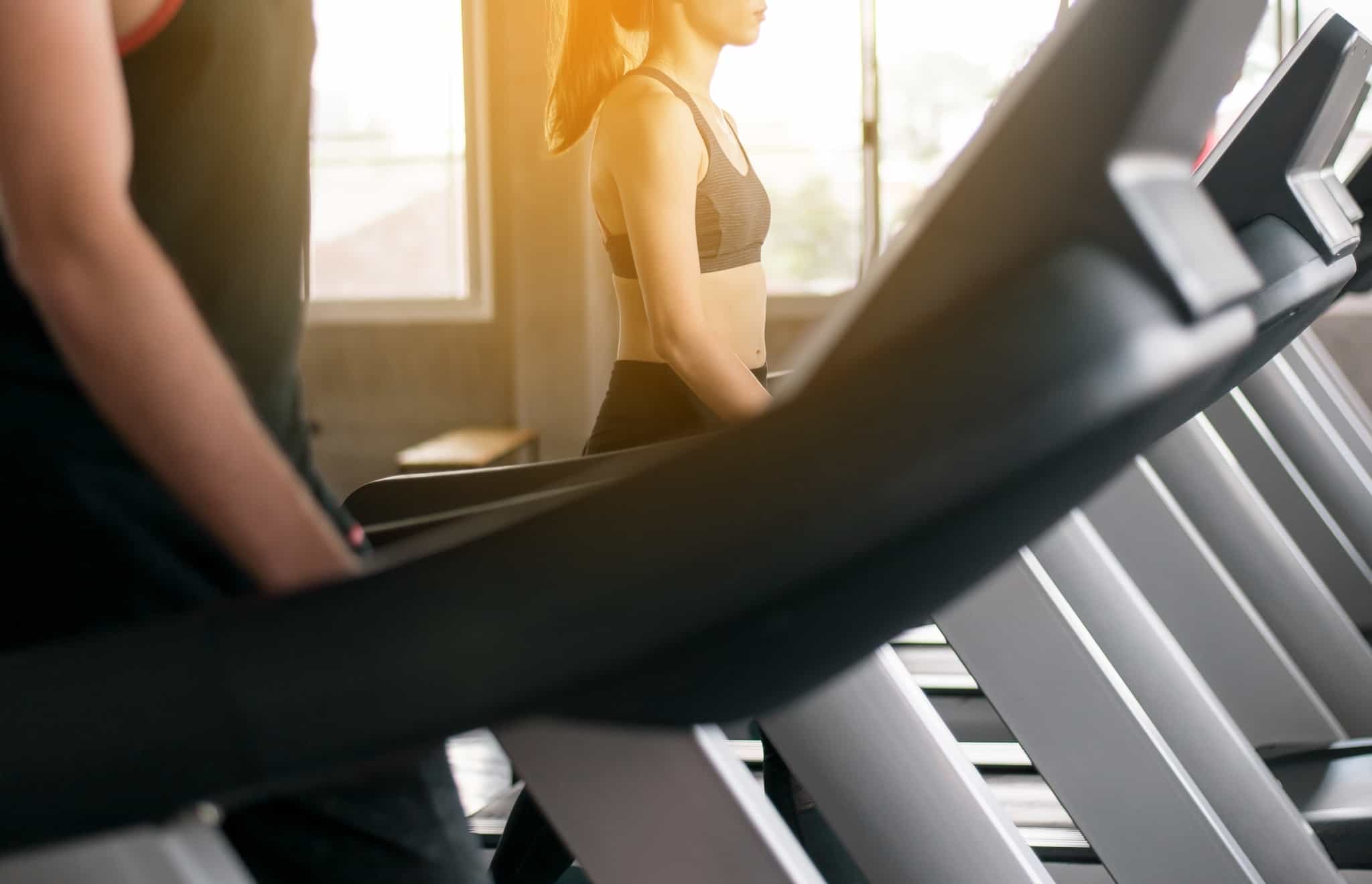 duas pessoas a correr na passadeira no ginasio