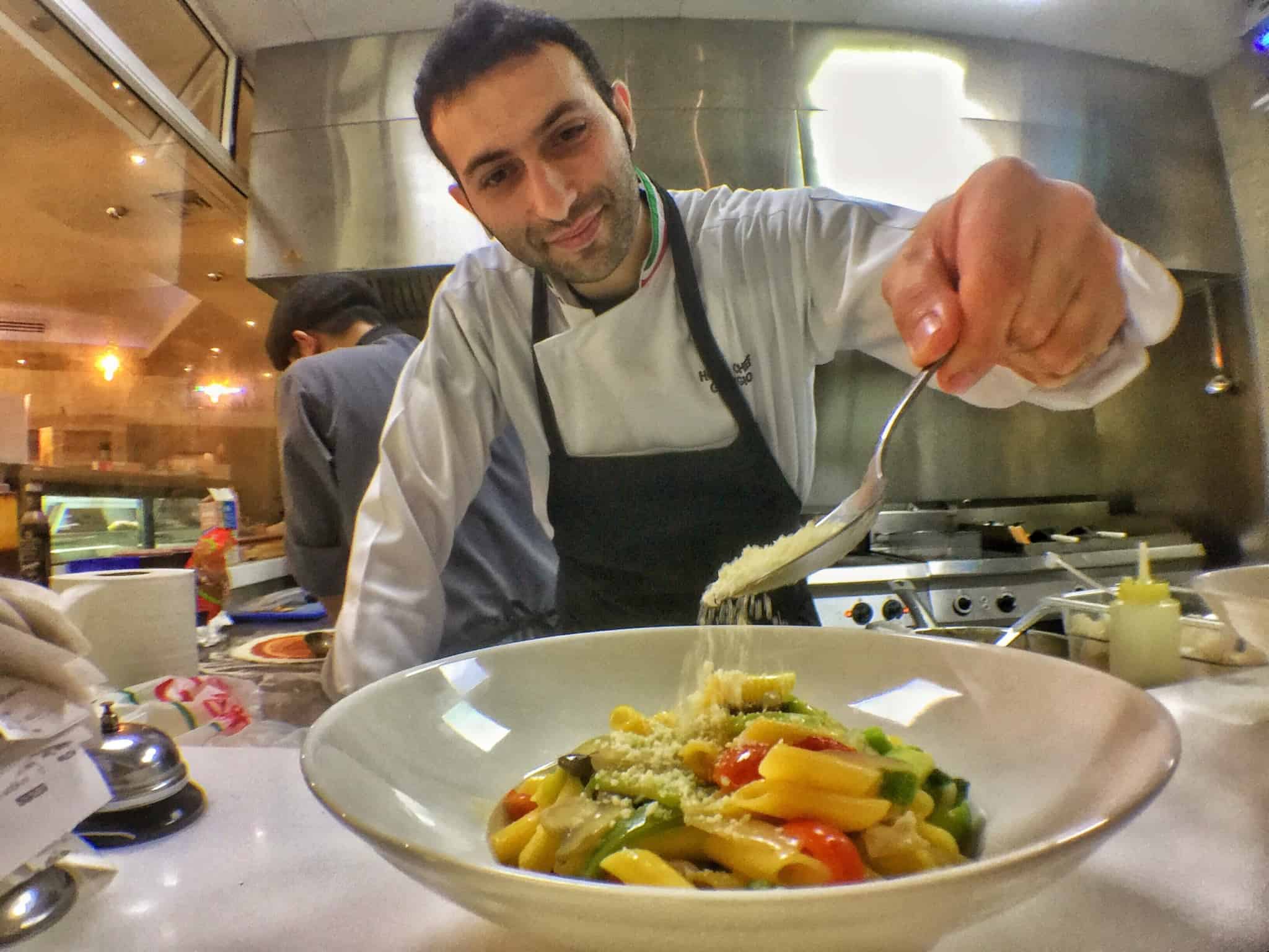 chef a colocar queijo num prato de massa