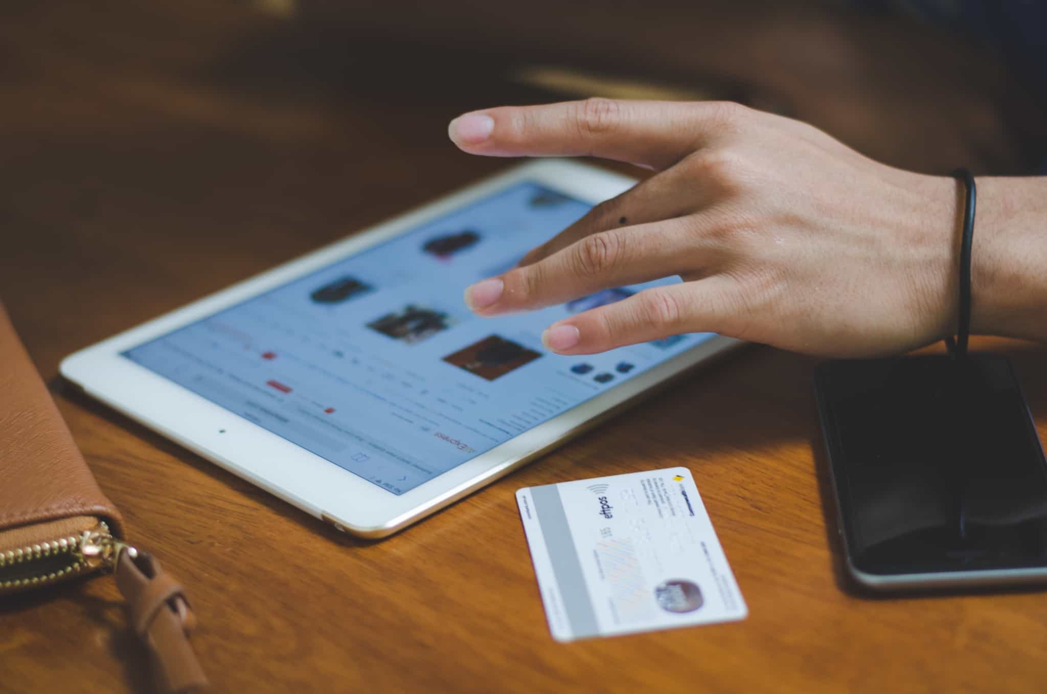 pessoa a fazer compras online no tablet com o cartão ao lado