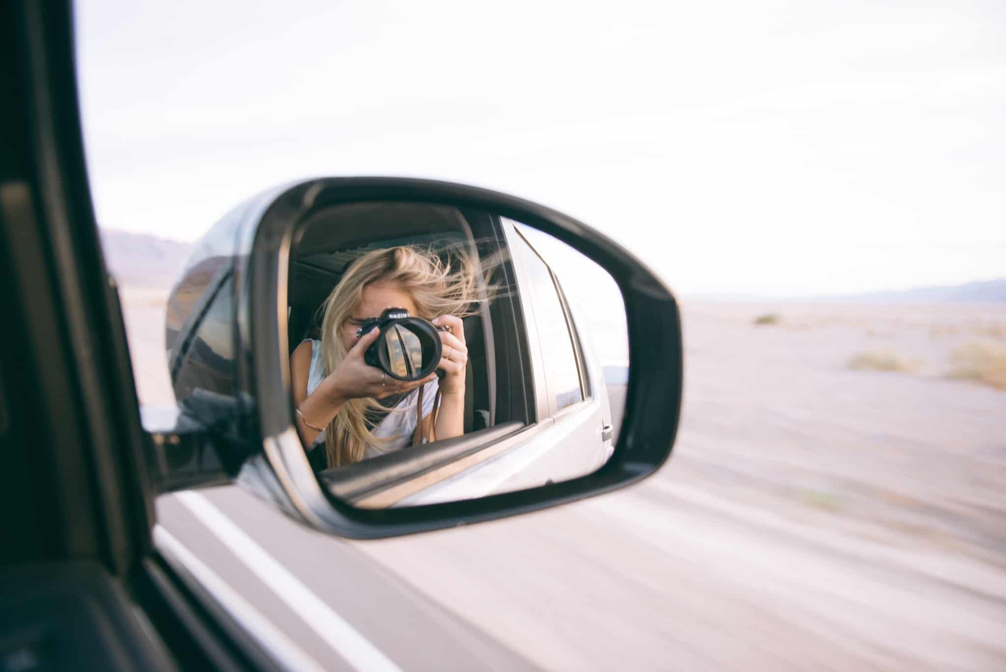 rapariga a tirar foto ao retrovisor de um carro