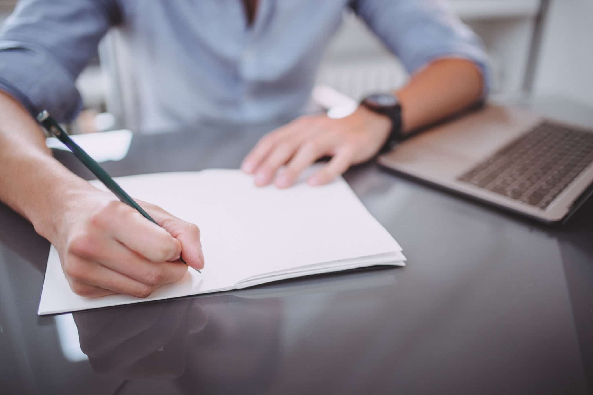 homem tira notas com lápis em caderno branco