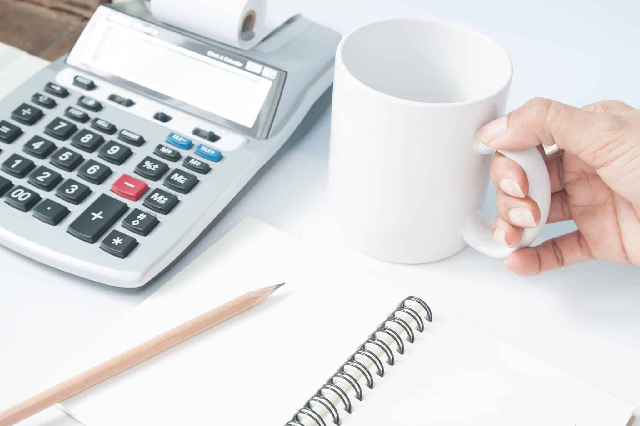contabilista com bloco de notas chavena de cafe e calculadora