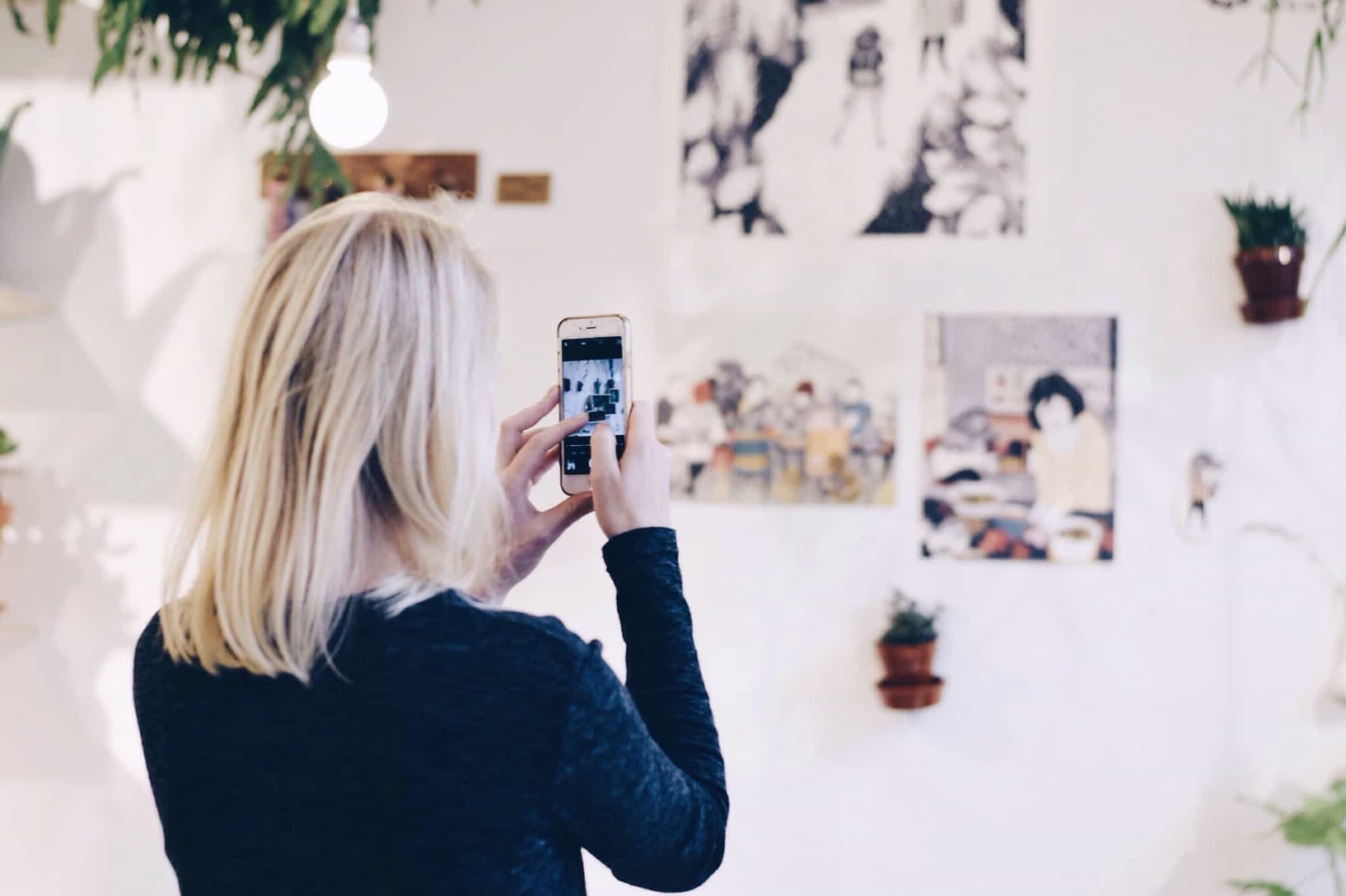 rapariga loira a tirar foto a parede com smartphone