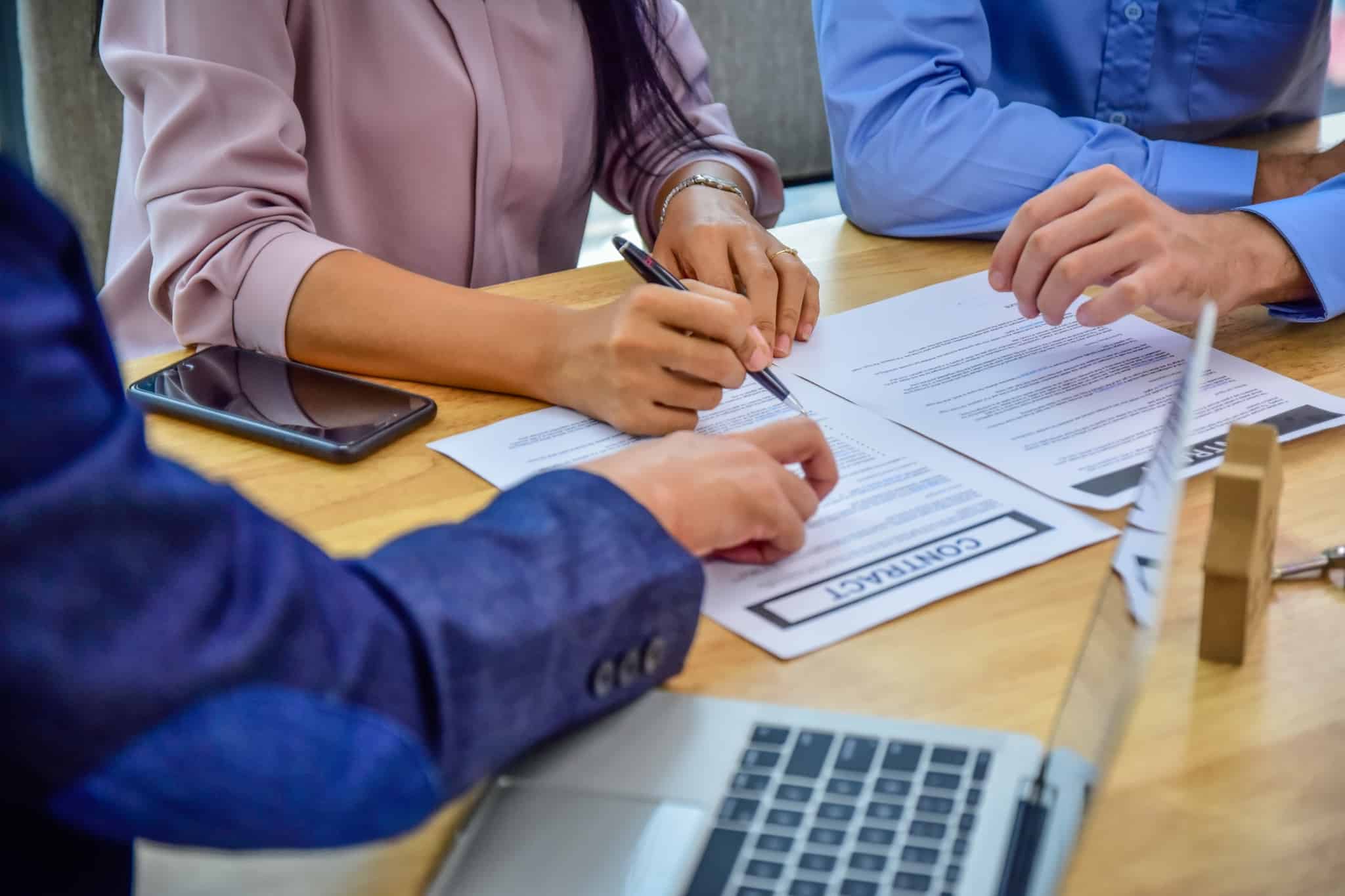 conversa entre 3 pessoas com um contrato a frente