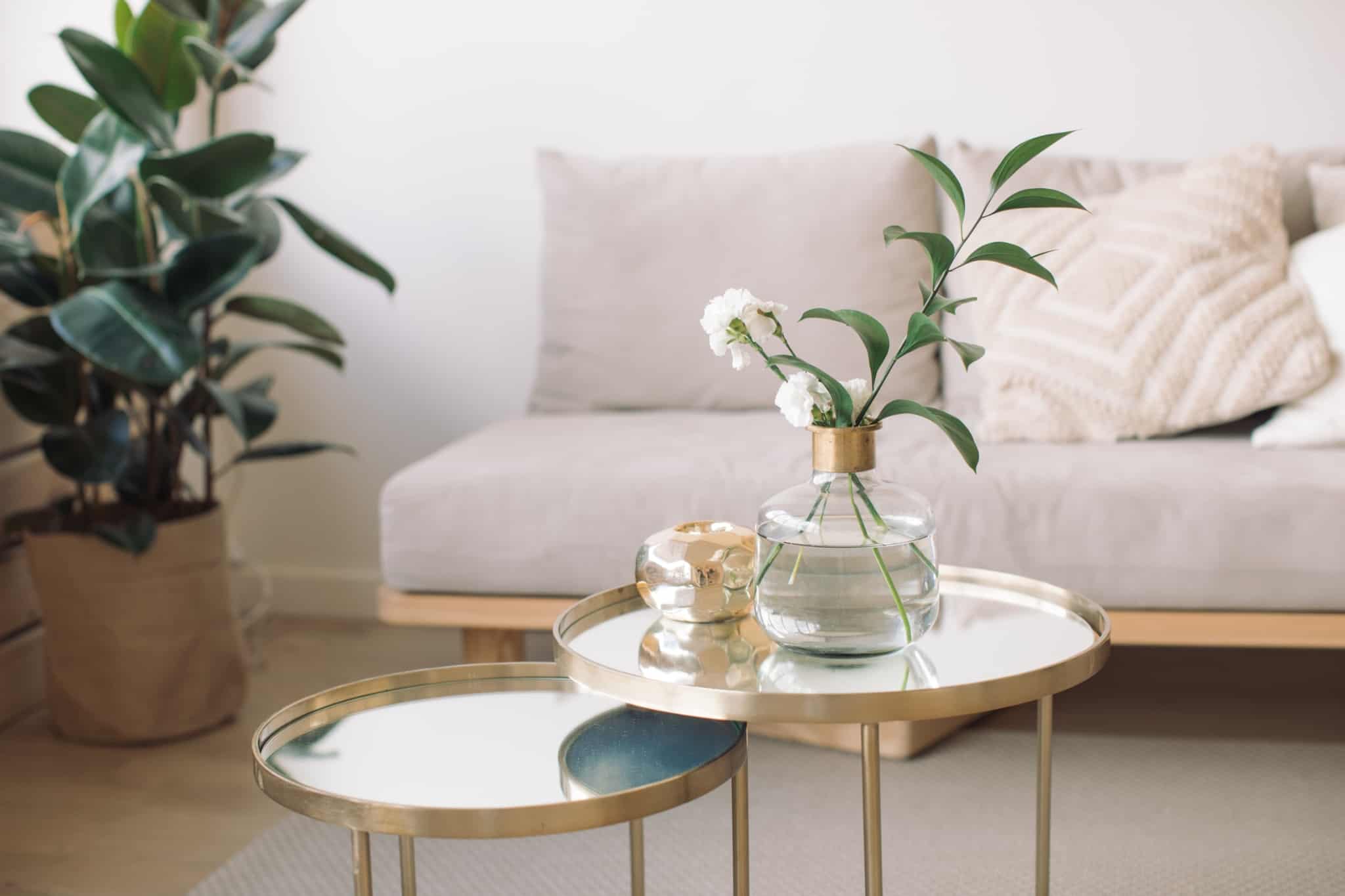 mesa de apoio em sala com flores e sofa creme