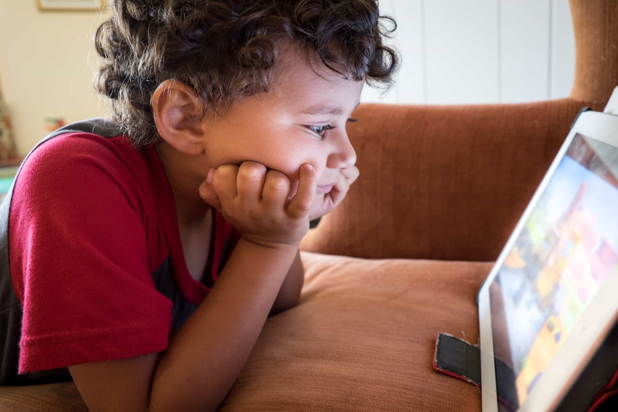 miudo a olhar para um tablet no sofa