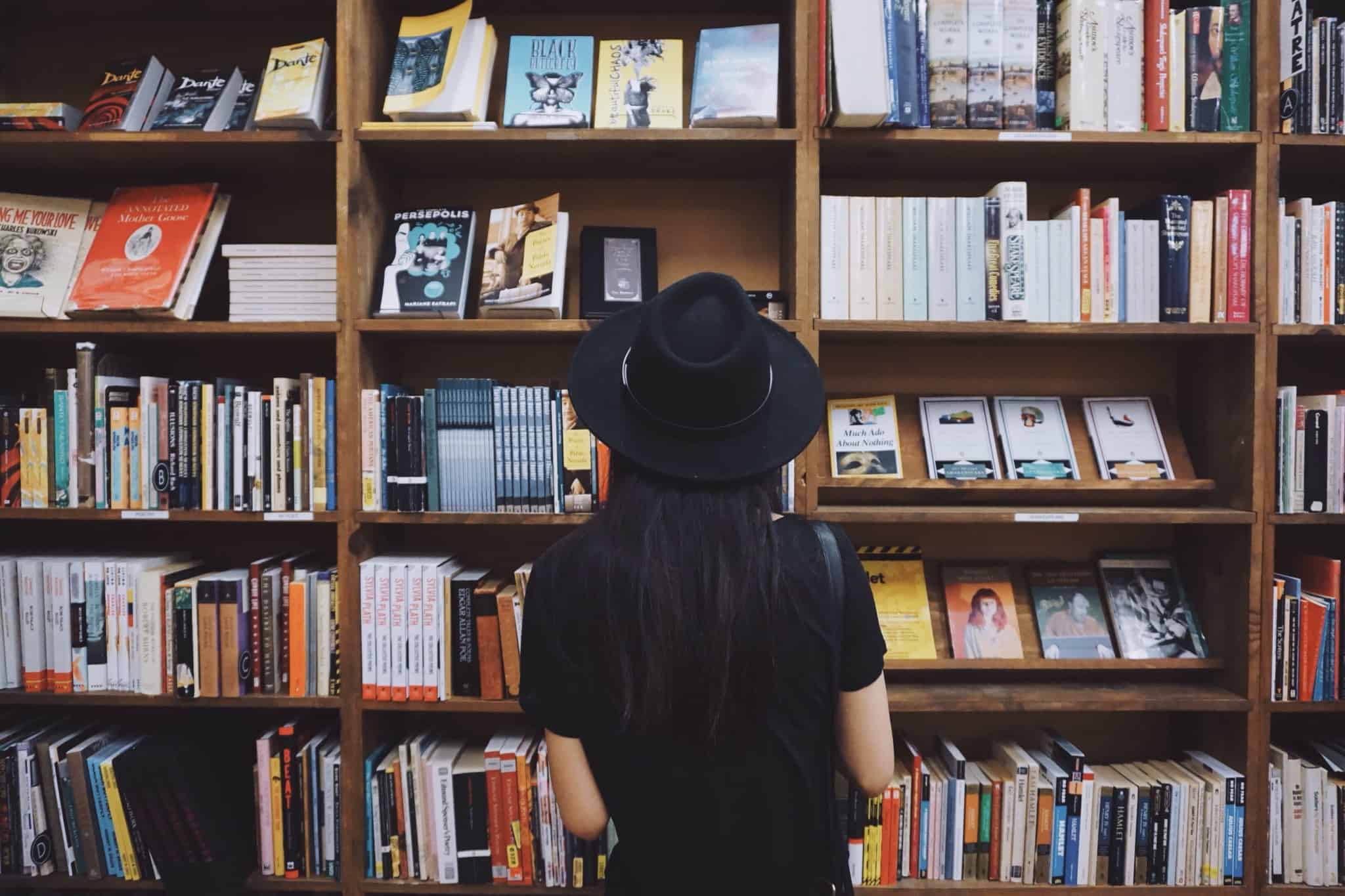 rapariga a olhar para estante de livros