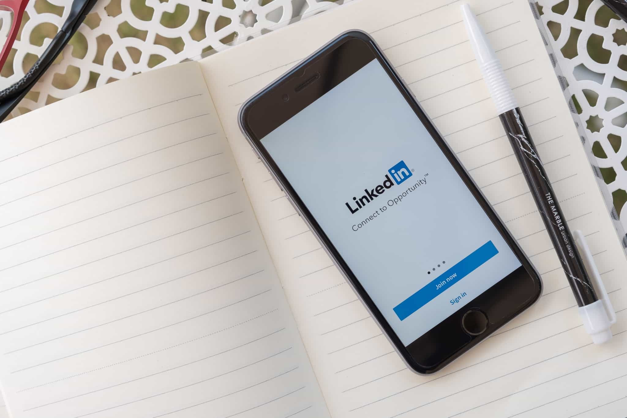 smartphone em cima do bloco de notas com o simbolo do linkedin