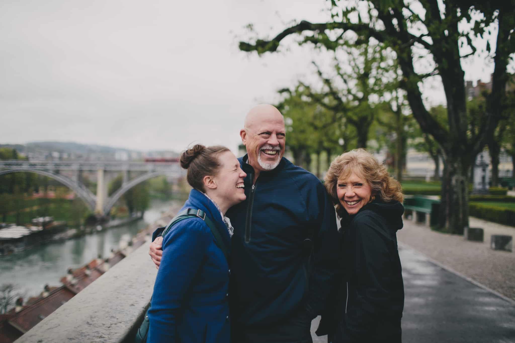 duas mulheres e um homem sorridente ao pé de uma ponte