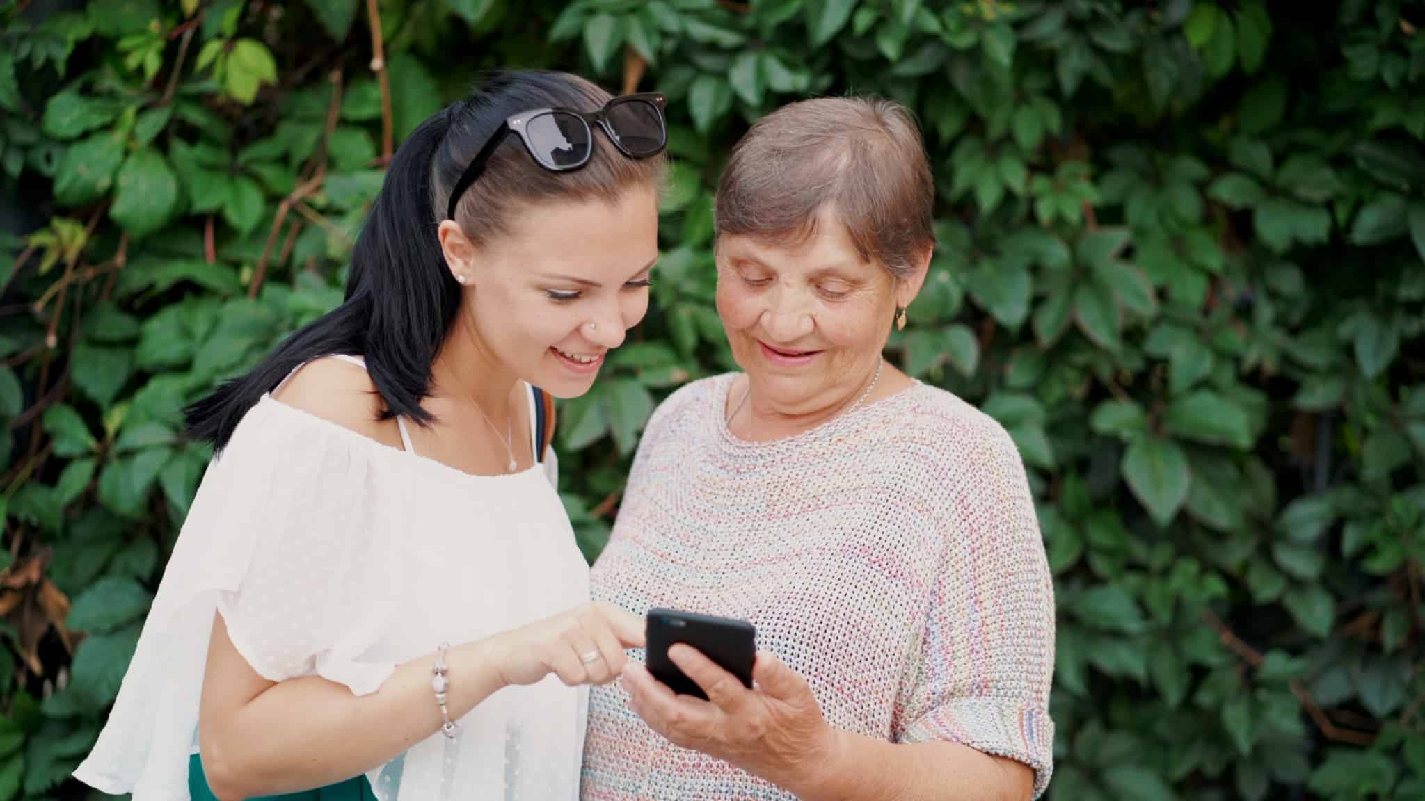 mãe mais velha e filha a olharem para o telemóvel
