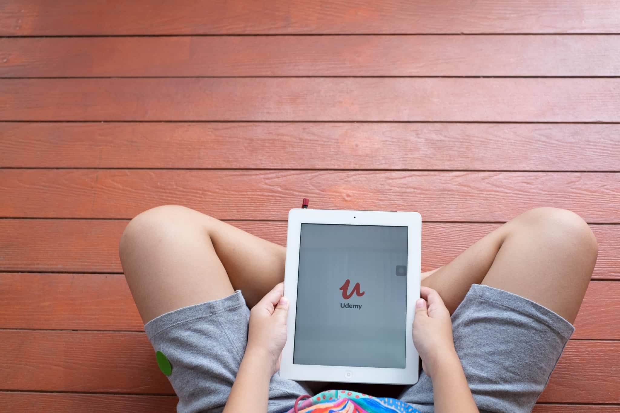 pessoa sentada com um tablet na mão com o portal udemy