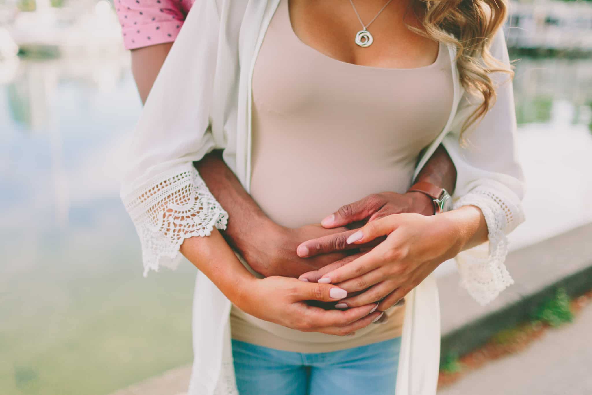 mãe grávida a ser abraçada por um homem