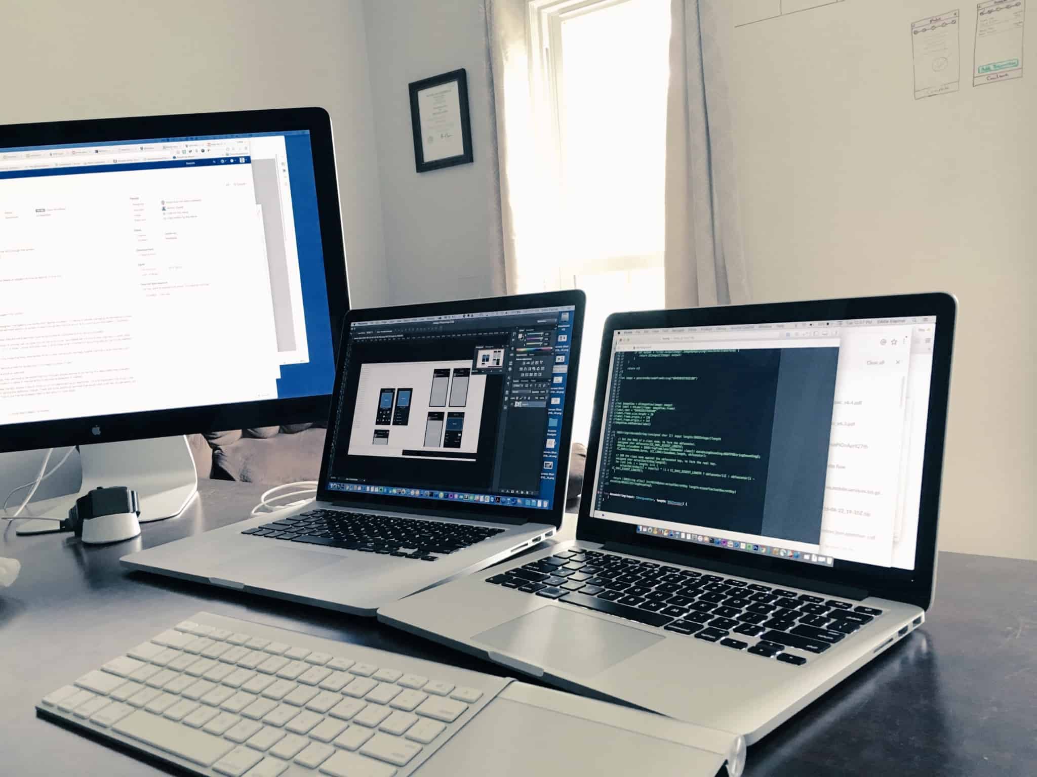dois computadores e um monitor em cima de uma secretária em casa