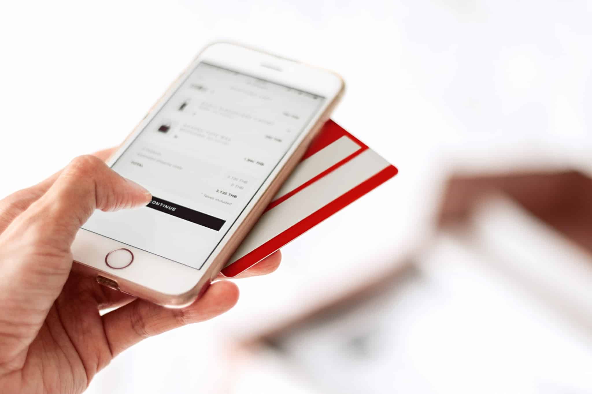 pessoa a fazer compras online no telemovel com o cartao atras