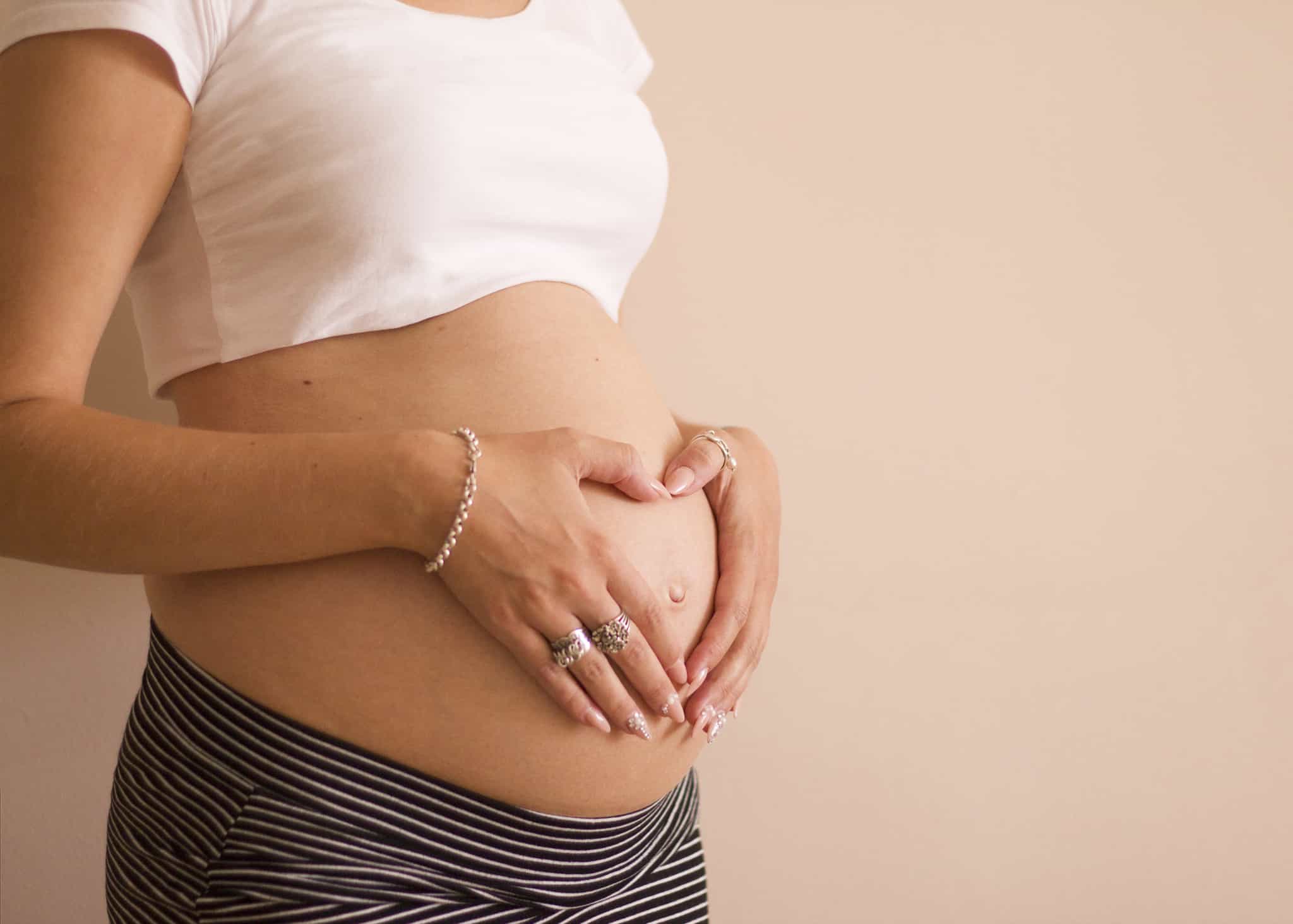 mulher grávida com as mãos em cima da barriga