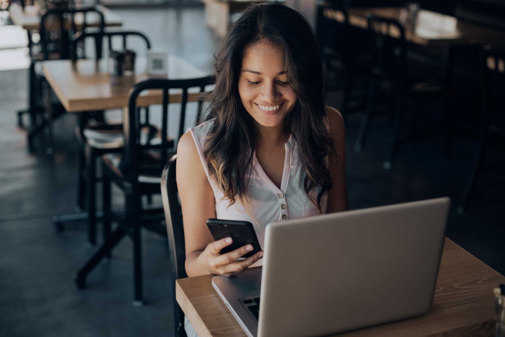 rapariga a trabalhar num cafe com portatil e telemovel