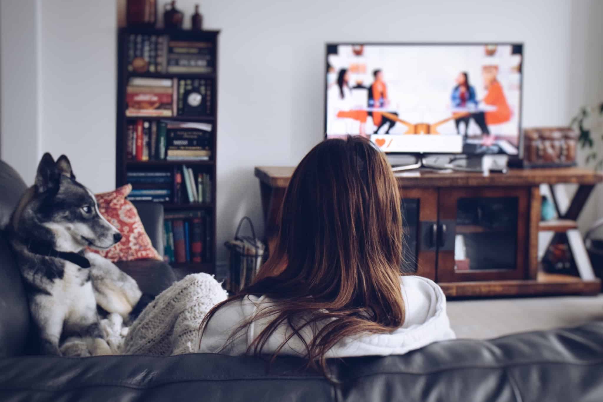 Rapariga a ver televisão ao lado do cão