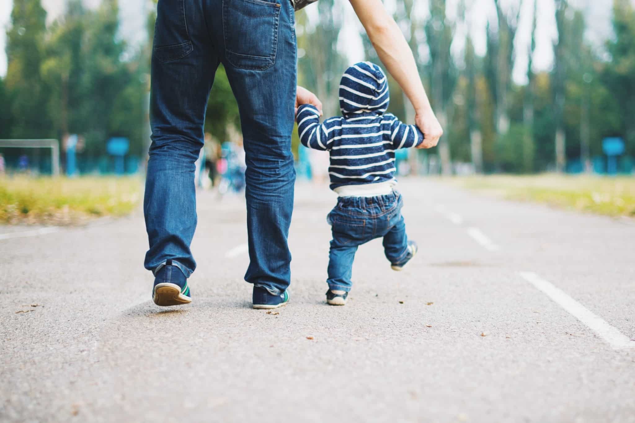 pai a passear com um bebe que está a aprender a andar