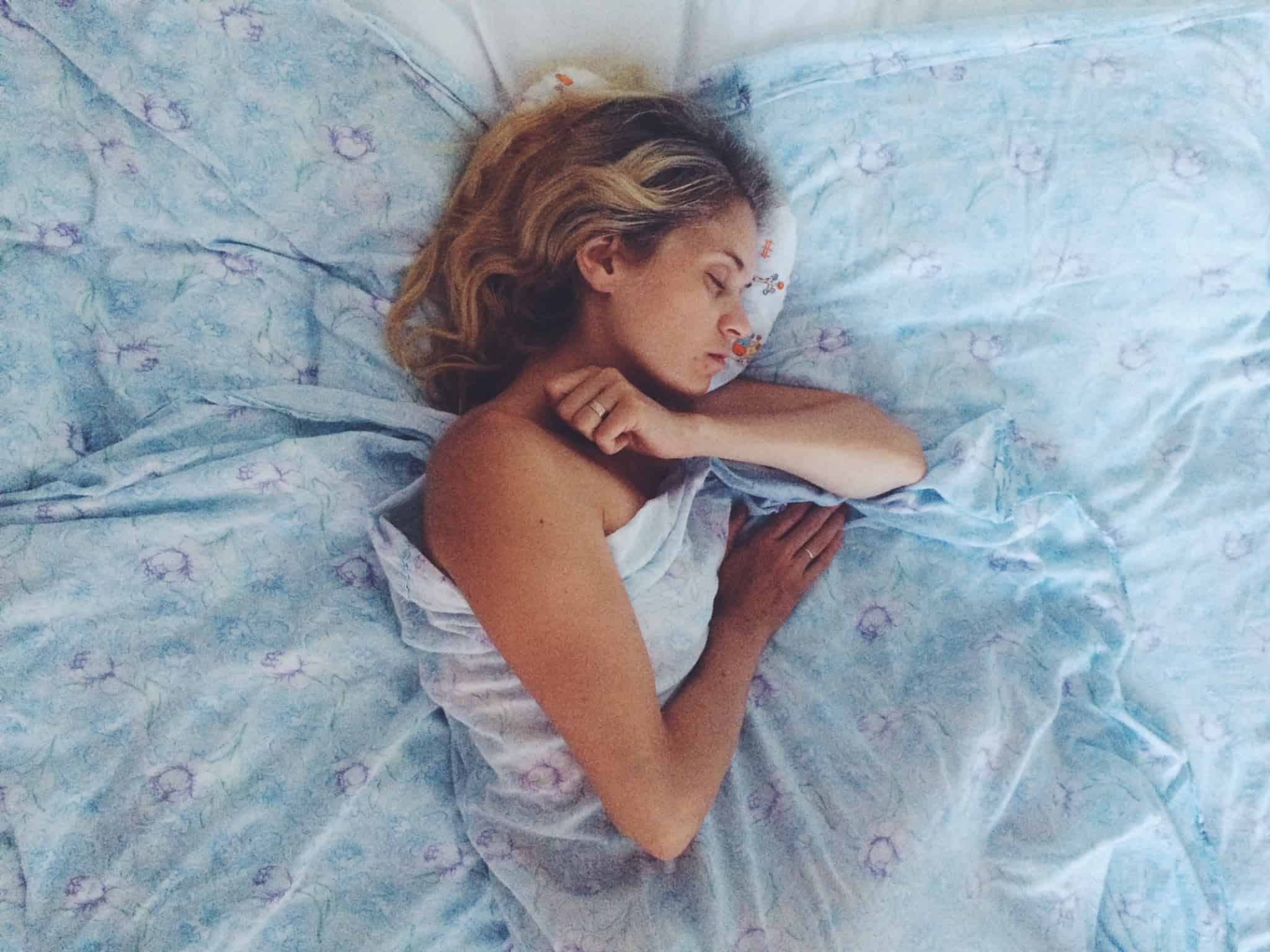 mulher loira a dormir num lençol azul
