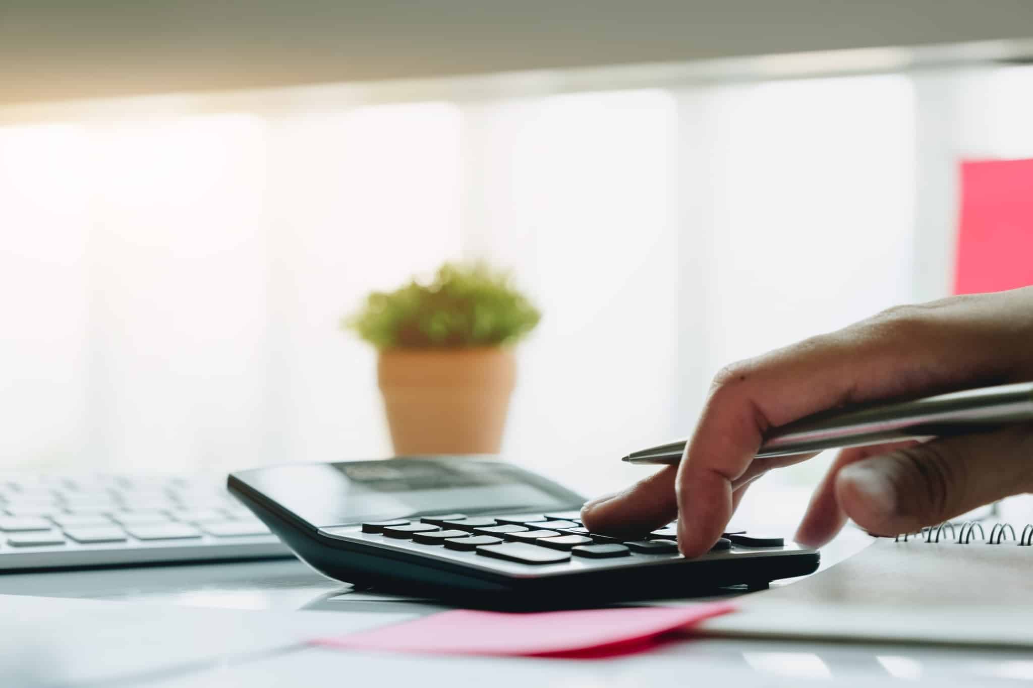 Uma caneta na mão, a fazer contas na máquina calculadora