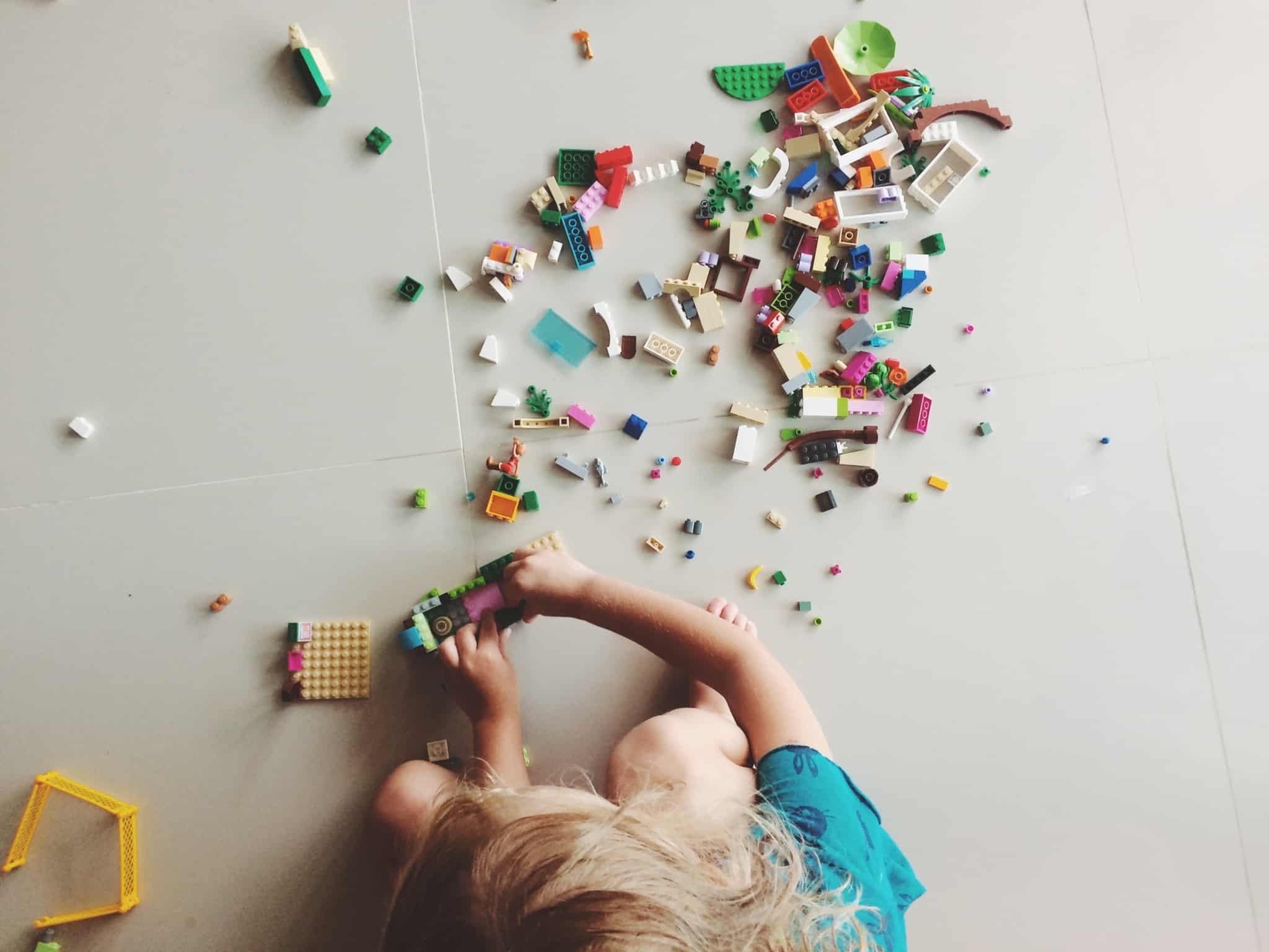criança a brincar com legos no chão