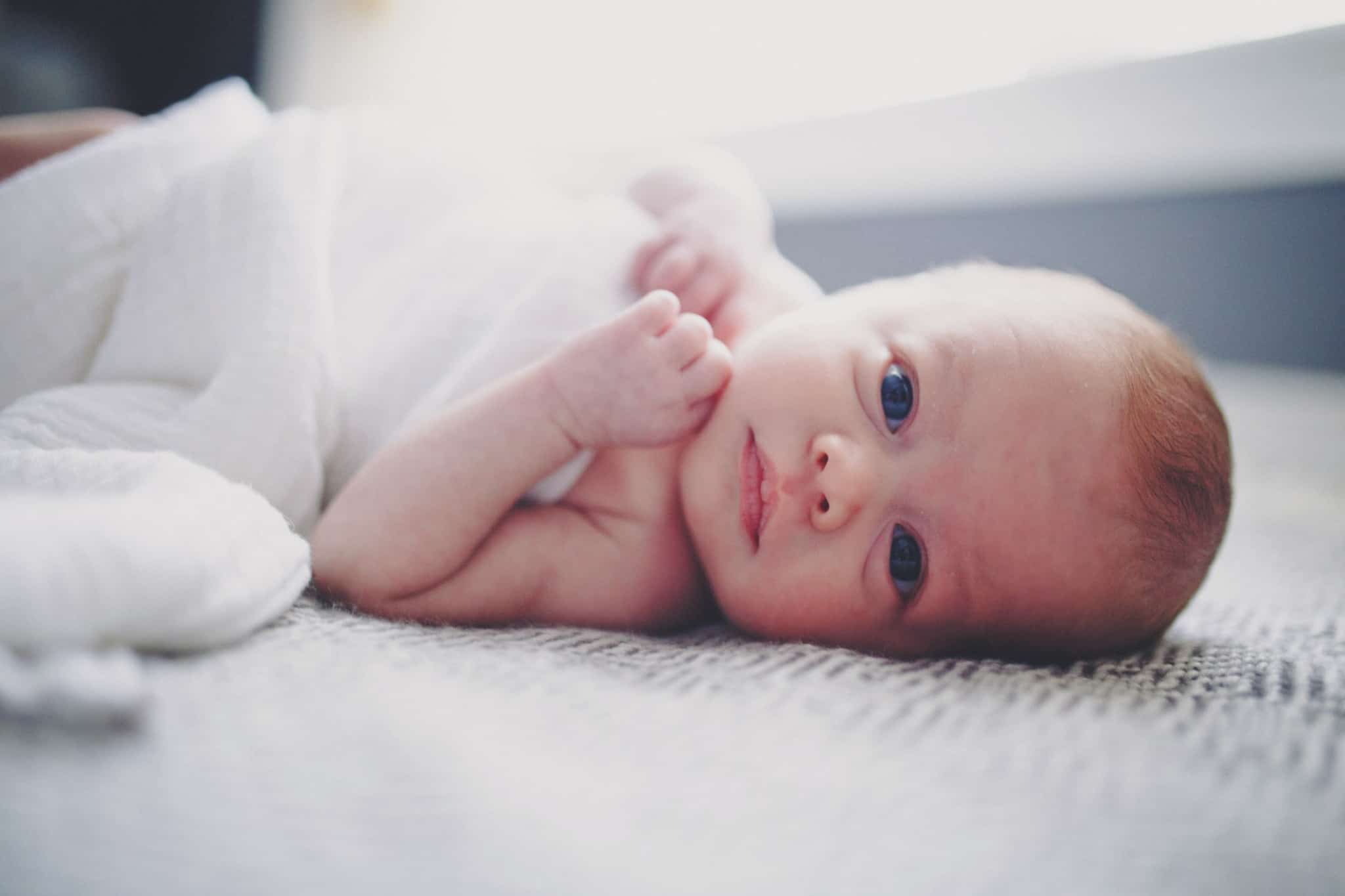 bebe de olhos azuis deitado na cama