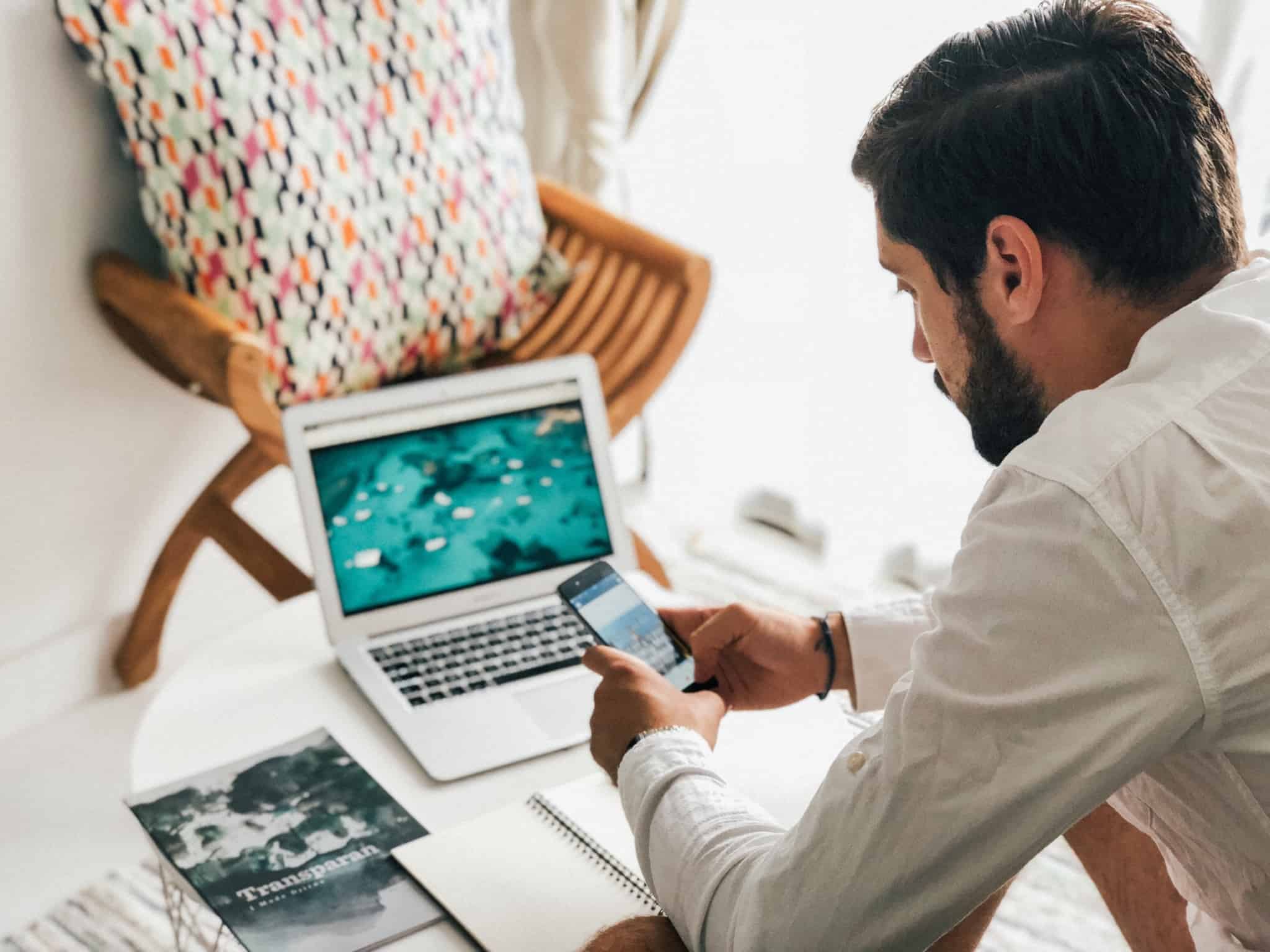 homem a mexer no telemóvel e no computador