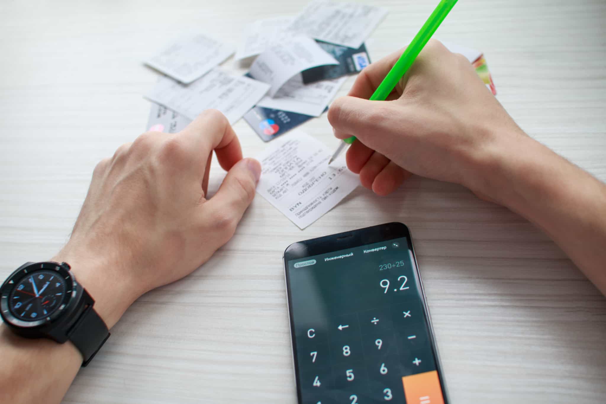 pessoa a fazer contas com vários talões e cartões de crédito em cima da mesa